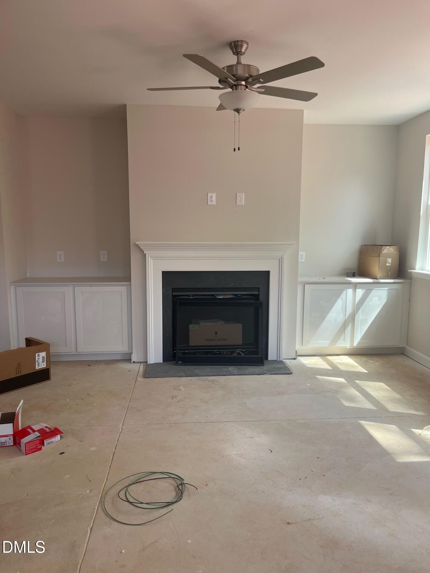 Cozy gas fireplace with built-in cabinets and ceiling fan in living room of Davidson Homes The Ashport G, Wake Forest NC