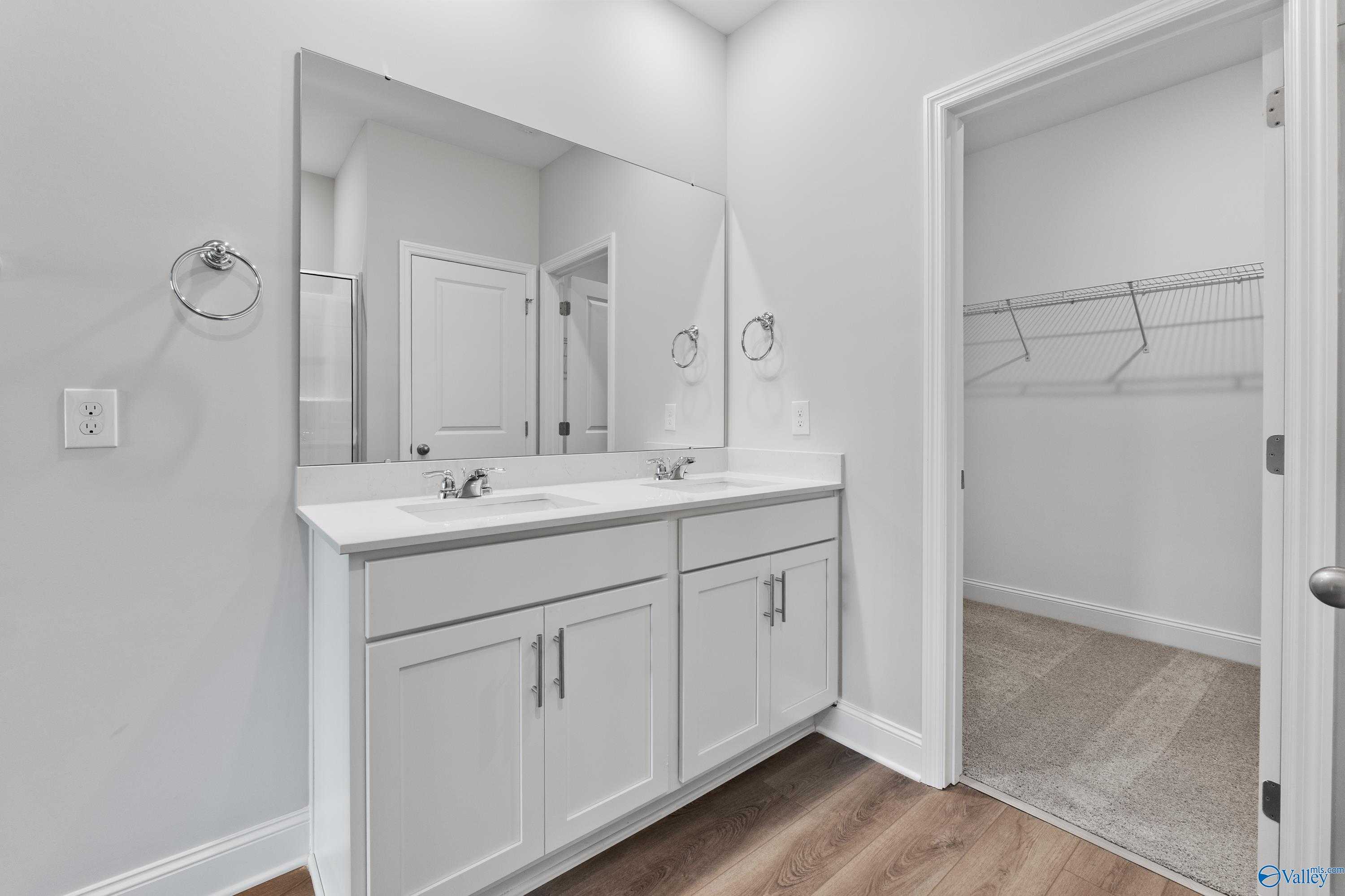Modern master bathroom featuring double white vanity, large mirrors, and walk-in closet in Davidson Homes The Franklin C, Toney, Alabama
