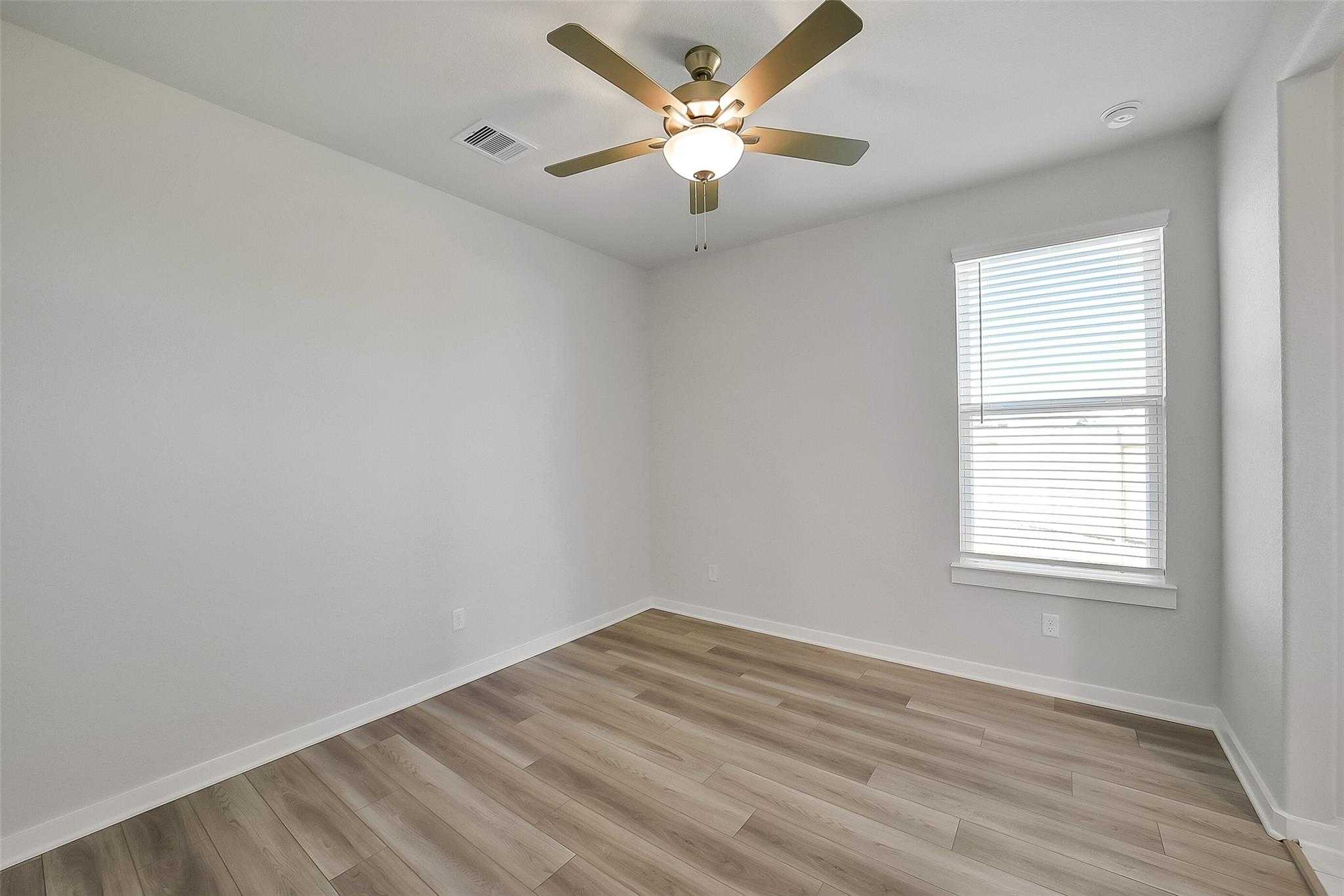 Bright bedroom with ceiling fan, luxury vinyl plank floors, and window blinds in Davidson Homes Acadia A, Sunterra, Katy, Texas