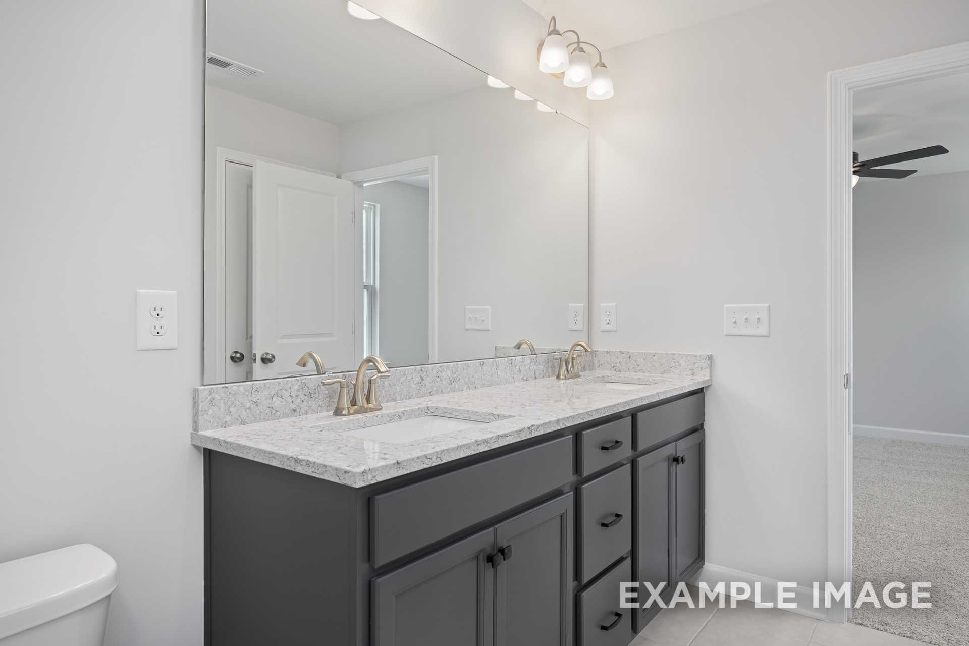 Spacious master bathroom in The Grace C with double quartz vanity, dark cabinets, and sconce lighting