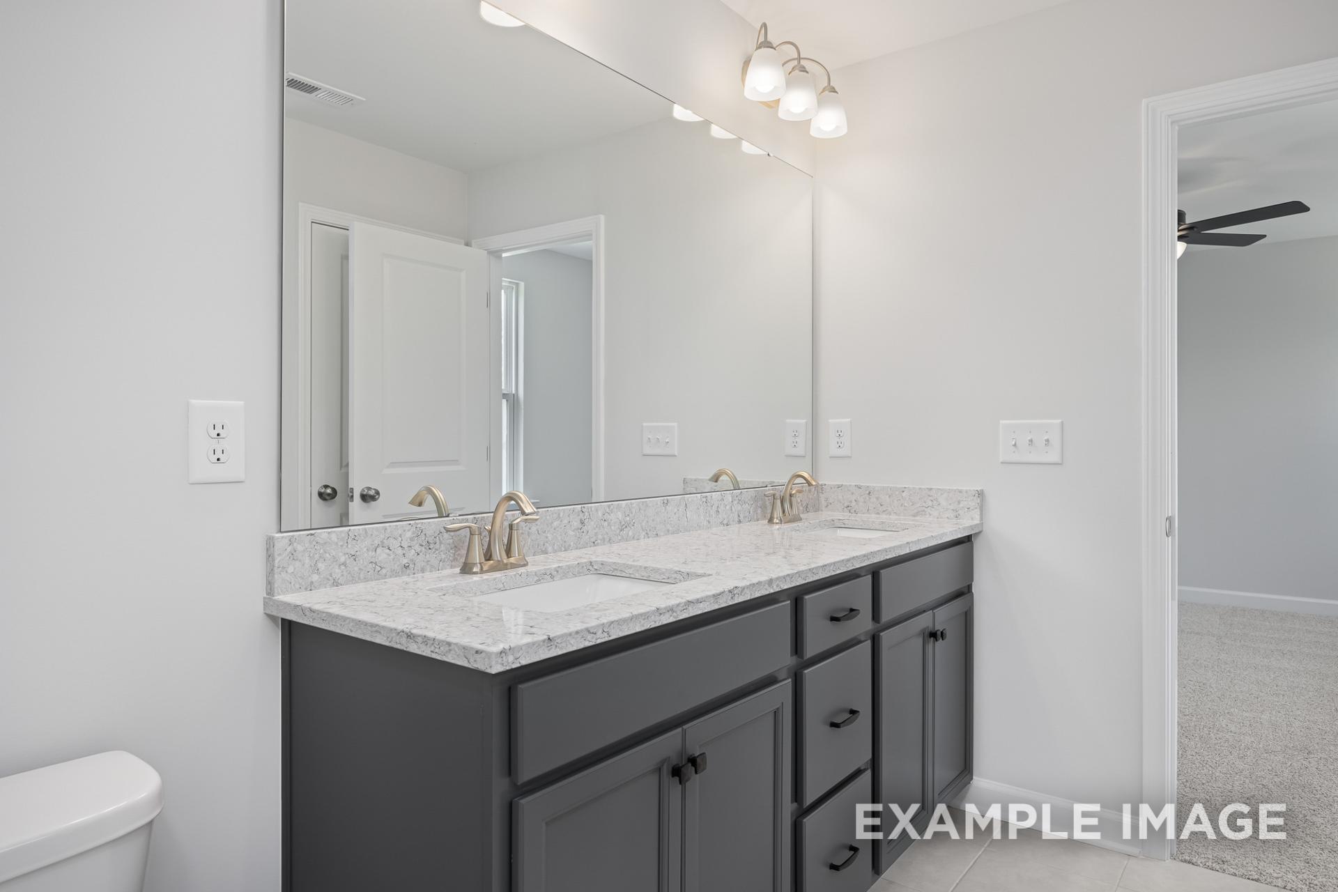 Spacious master bathroom in The Grace C with double quartz vanity, dark cabinets, and sconce lighting