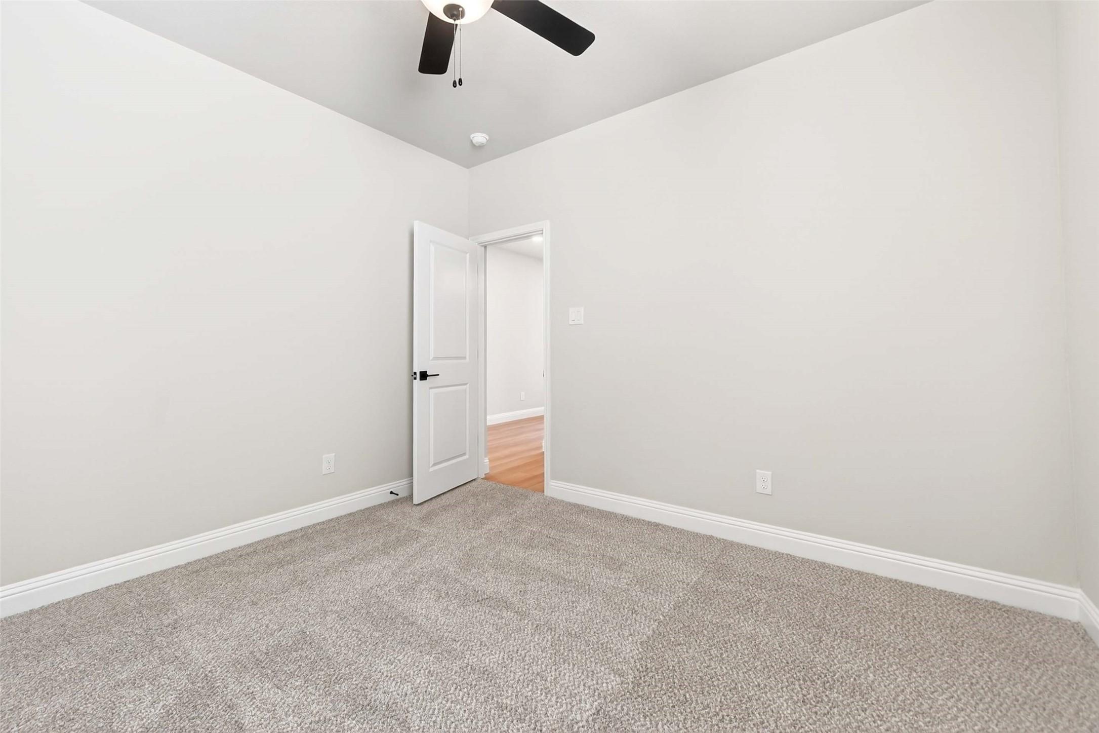 Spacious bedroom with plush carpeting and ceiling fan in The Holly C floor plan at Parks at Foster Crossing, Anna, Texas.