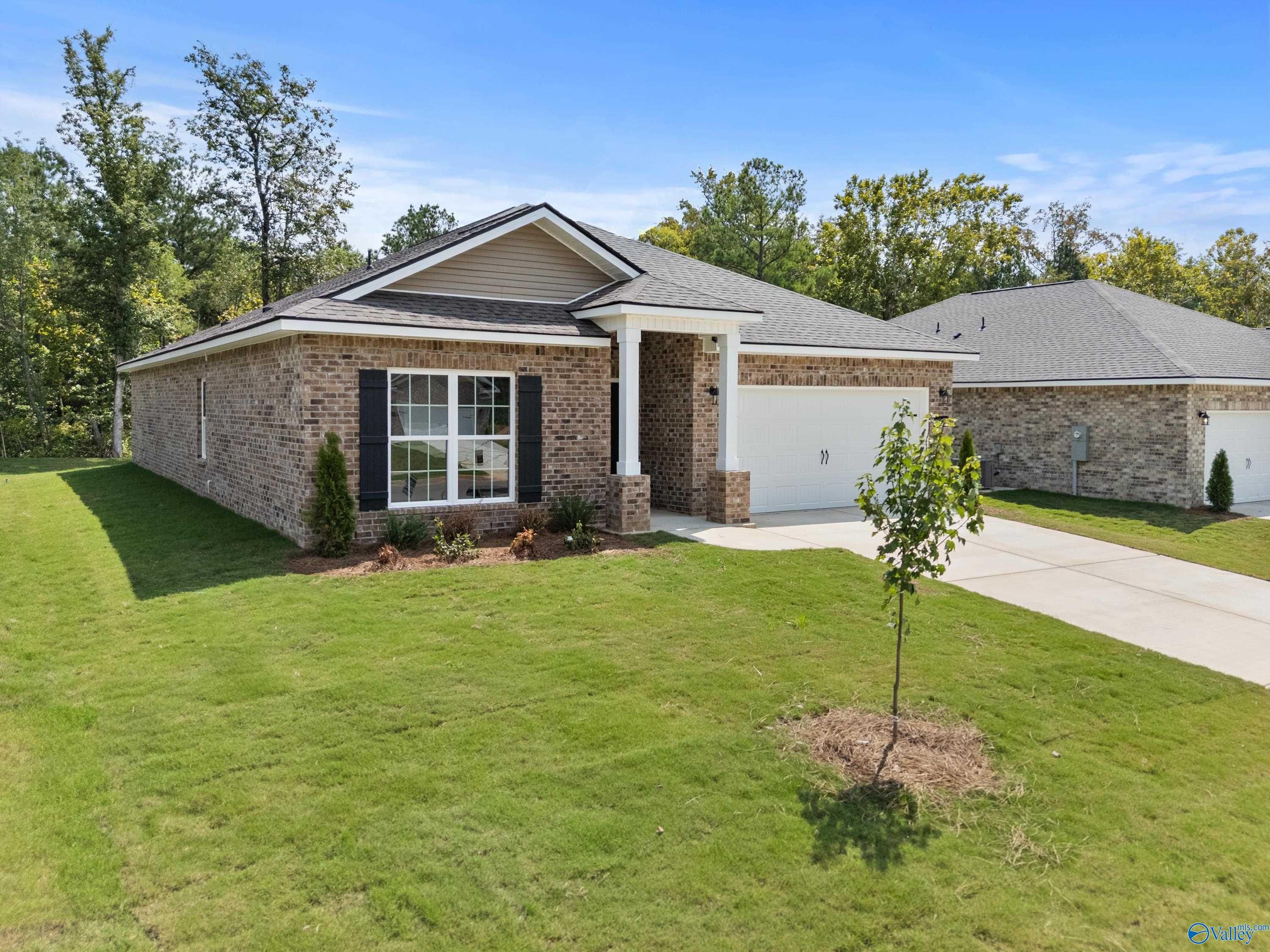 Modern brick single-story 4-bedroom home with 2-car garage, covered porch, and lush lawn in Spragins Cove, Huntsville, Alabama