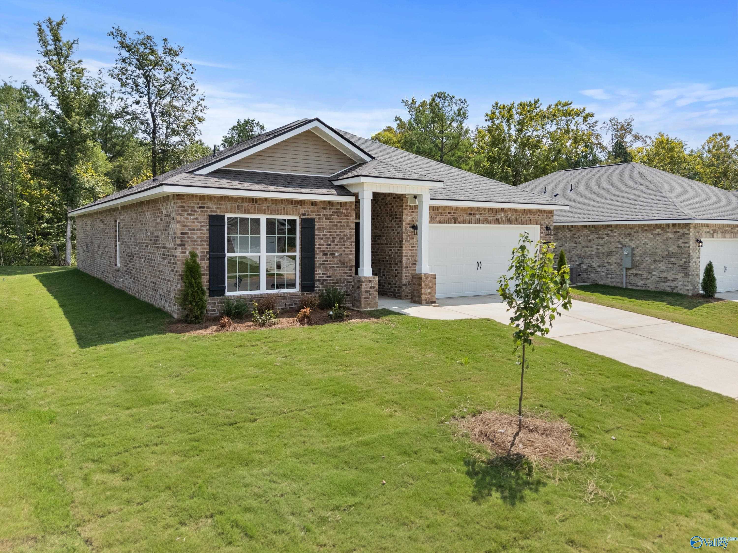 Modern brick single-story 4-bedroom home with 2-car garage, covered porch, and lush lawn in Spragins Cove, Huntsville, Alabama