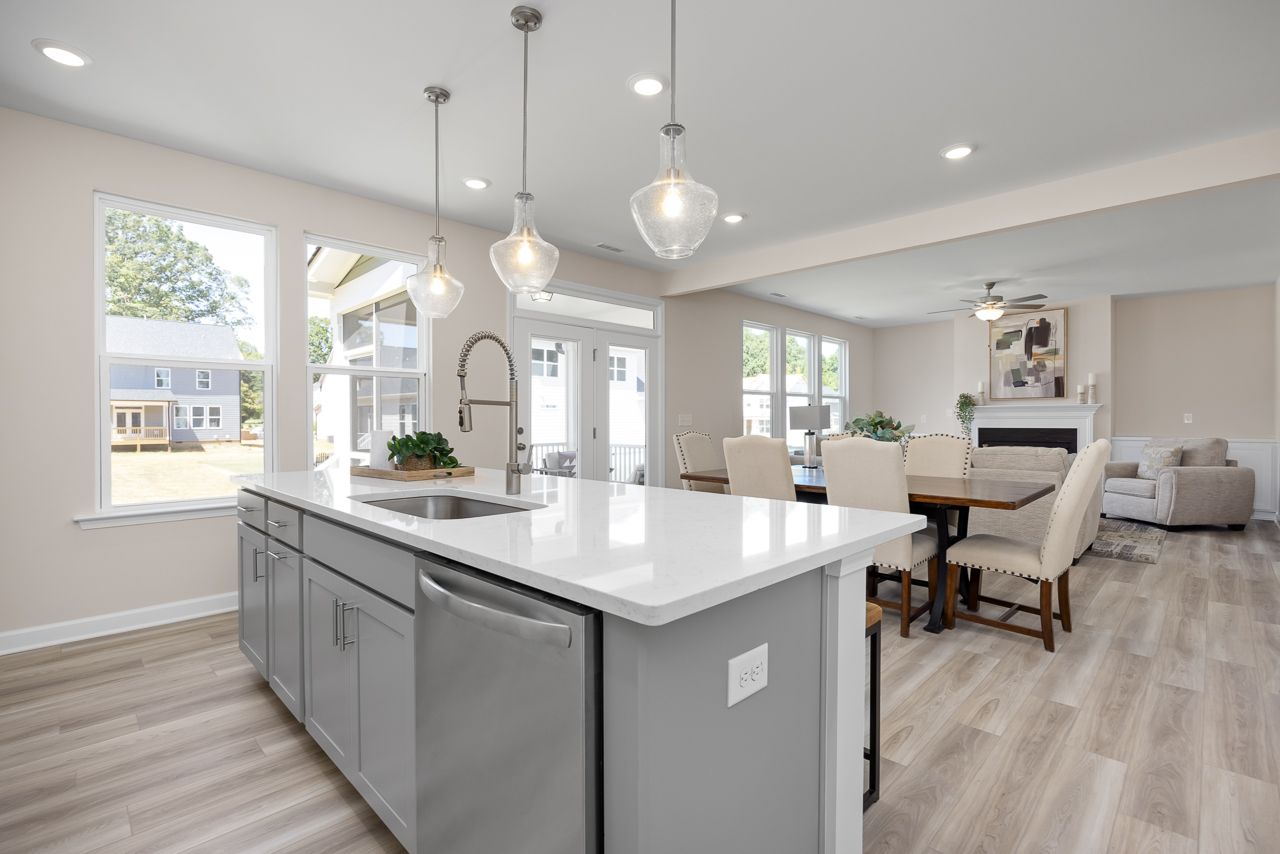 Open-concept kitchen and dining area in The Chestnut with a large island, modern gray cabinetry, and hardwood floors.
