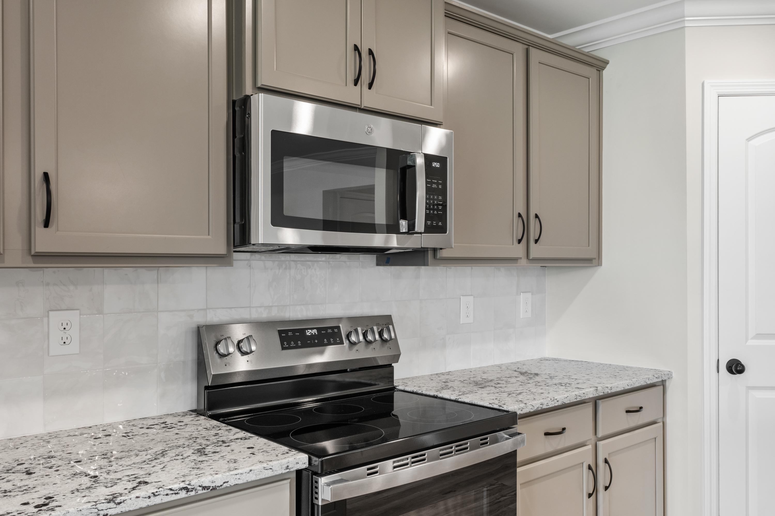 Modern kitchen in The Everett D with stainless steel range, microwave, beige cabinets, subway tile backsplash