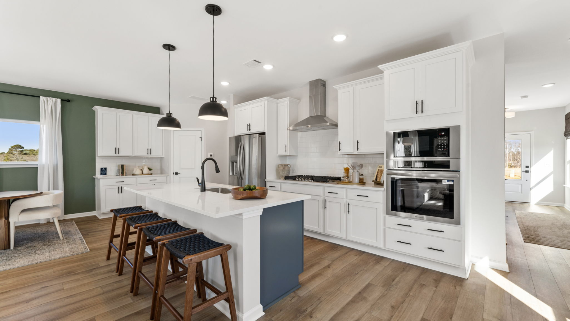 Modern kitchen in The Bluffs model home with white cabinets, navy island, stainless appliances, pendant lights for Davidson Homes Atlanta grand opening