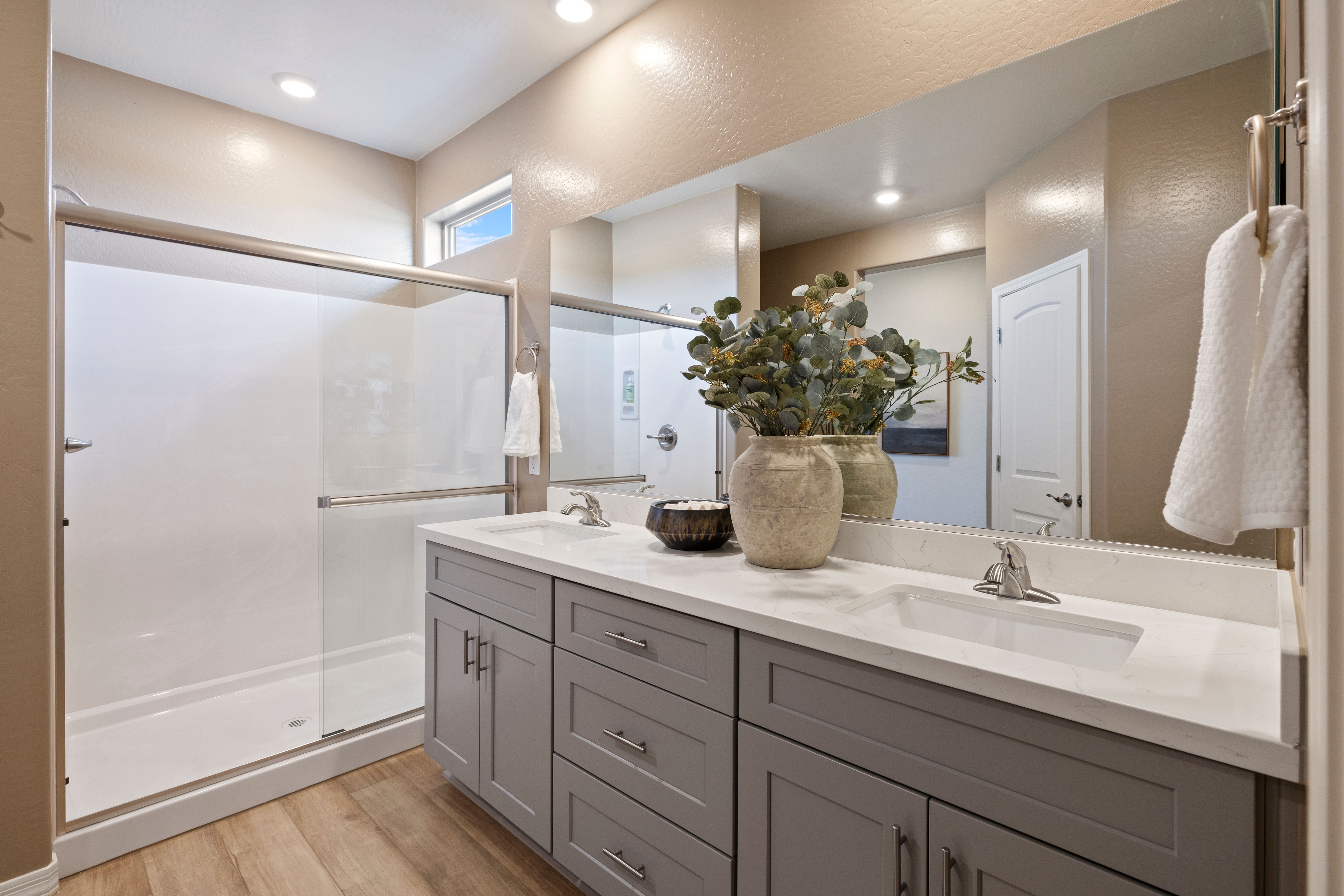 Spacious bathroom at North Ridge Pronghorn Ranch in Prescott Valley AZ with double gray vanity, eucalyptus decor, and glass shower