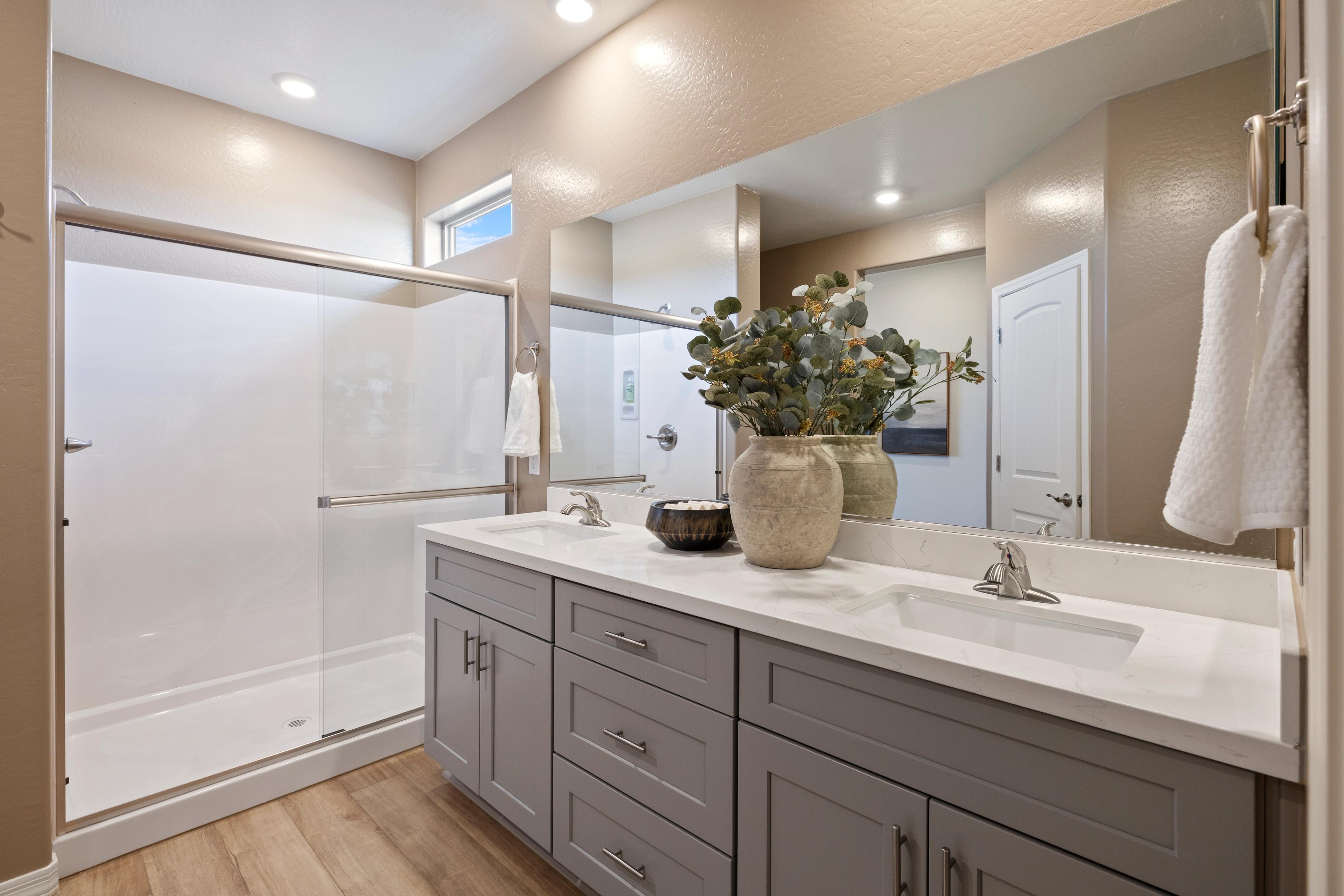 Spacious bathroom at North Ridge Pronghorn Ranch in Prescott Valley AZ with double gray vanity, eucalyptus decor, and glass shower