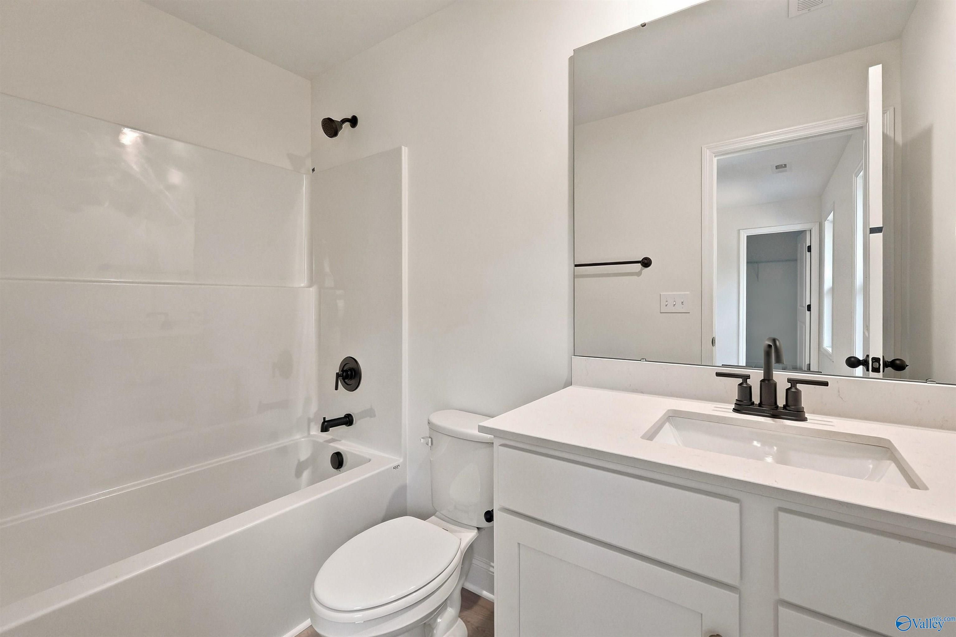 Modern bathroom with white vanity, tub-shower combo, and matte black fixtures in The Chelsea C home, Creek Grove, Alabama.