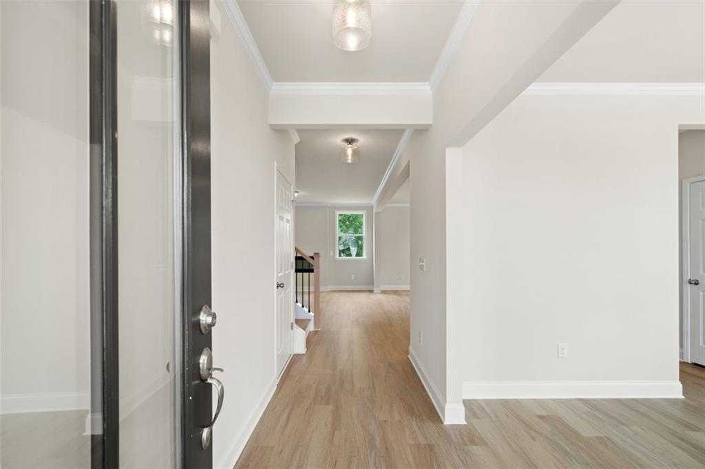 Bright entry foyer with light hardwood floors, white walls, glass front door in The Willow B, Hoschton, Georgia