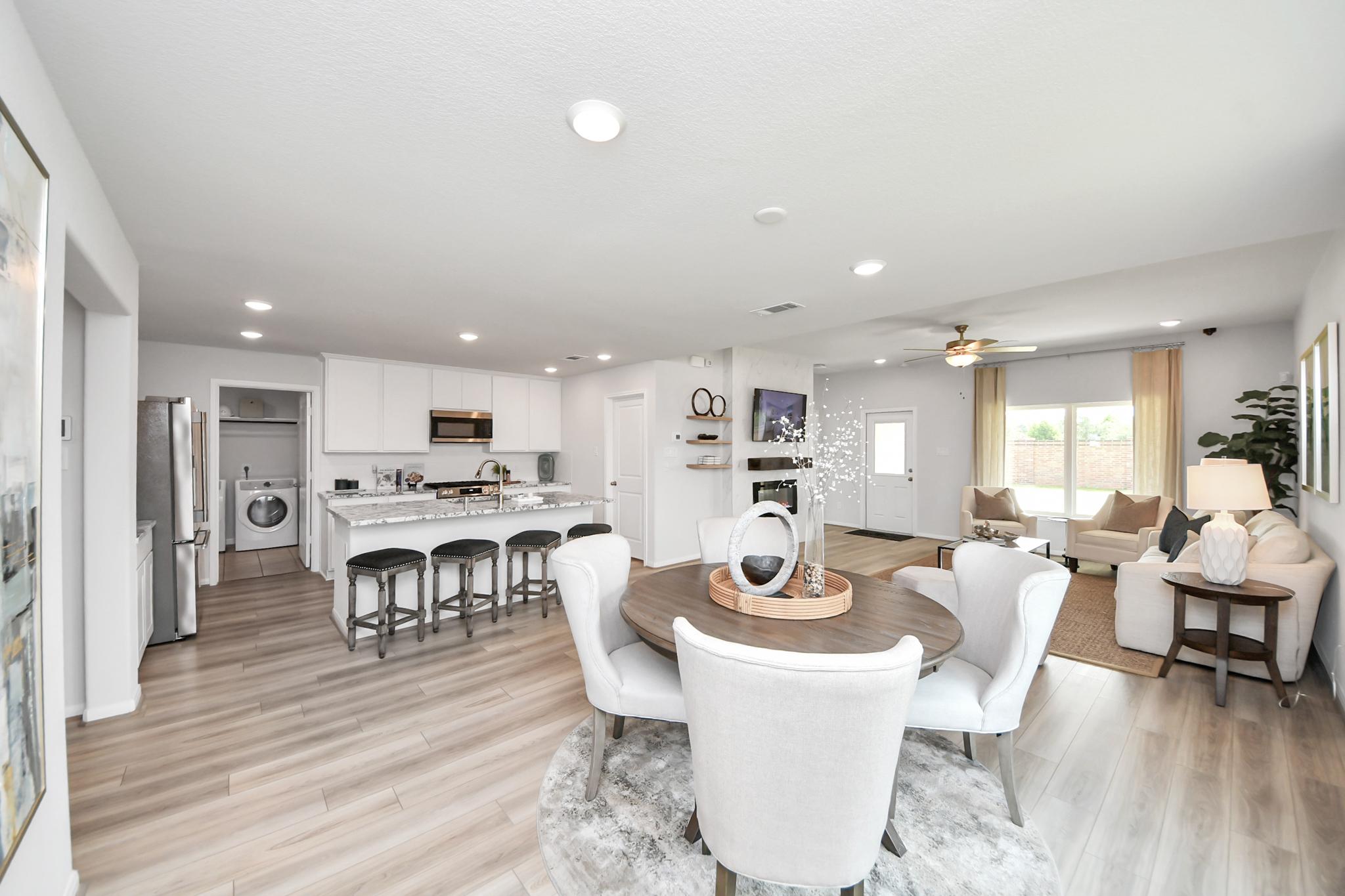 Open-concept living and dining area at Sunterra in Katy, TX by Davidson Homes with modern kitchen and wood-style flooring.