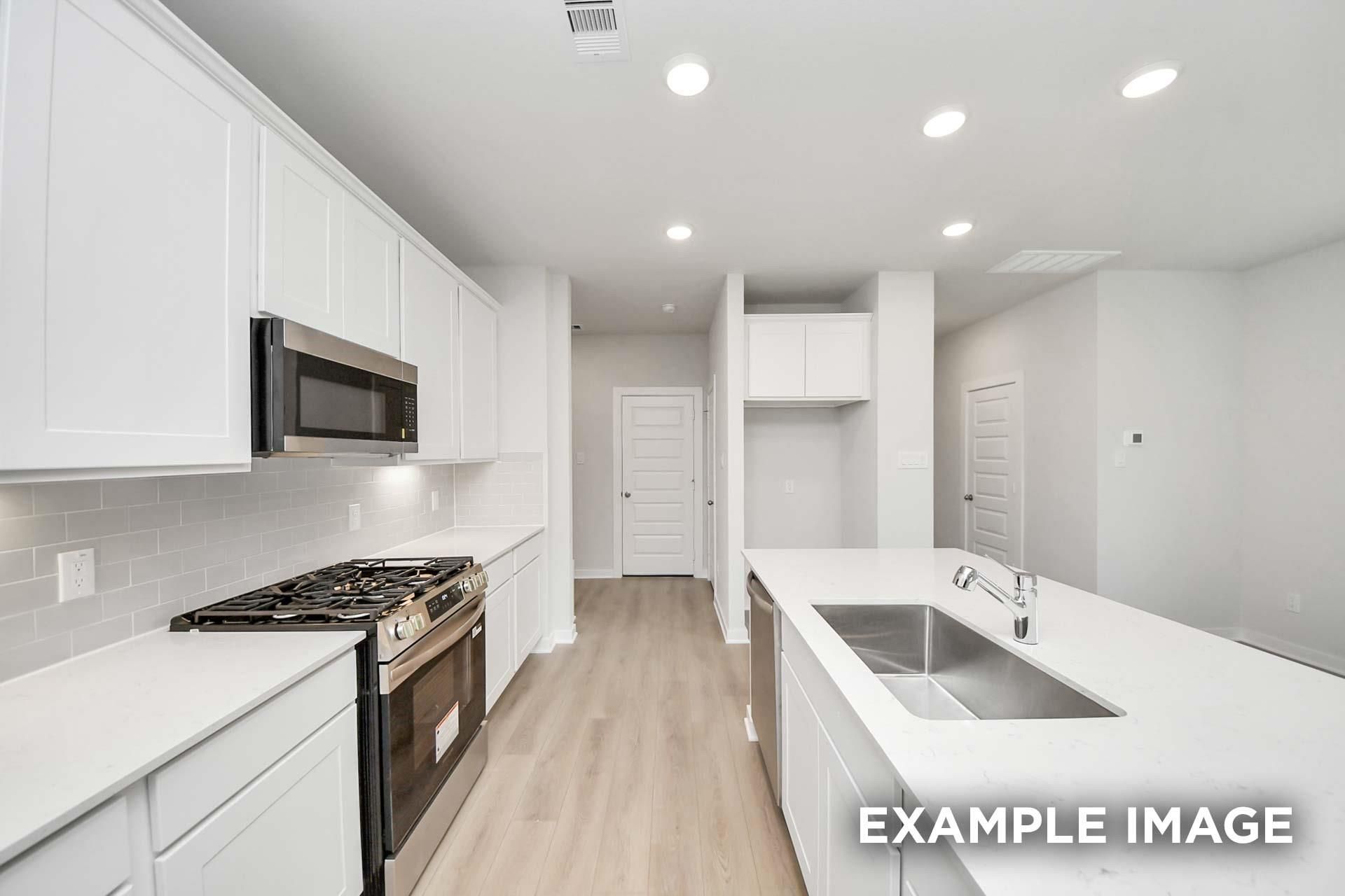Bright modern kitchen with white shaker cabinets, stainless gas range, island with sink, and subway tile backsplash in The Blanco E, Magnolia, TX