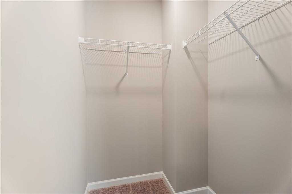 Spacious walk-in closet with white wire shelving on beige walls in Davidson Homes The Bartlett, Phenix City, Alabama
