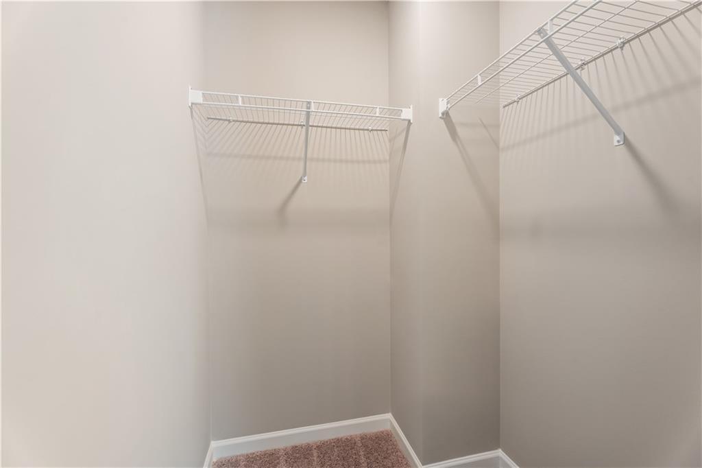 Spacious walk-in closet with white wire shelving on beige walls in Davidson Homes The Bartlett, Phenix City, Alabama