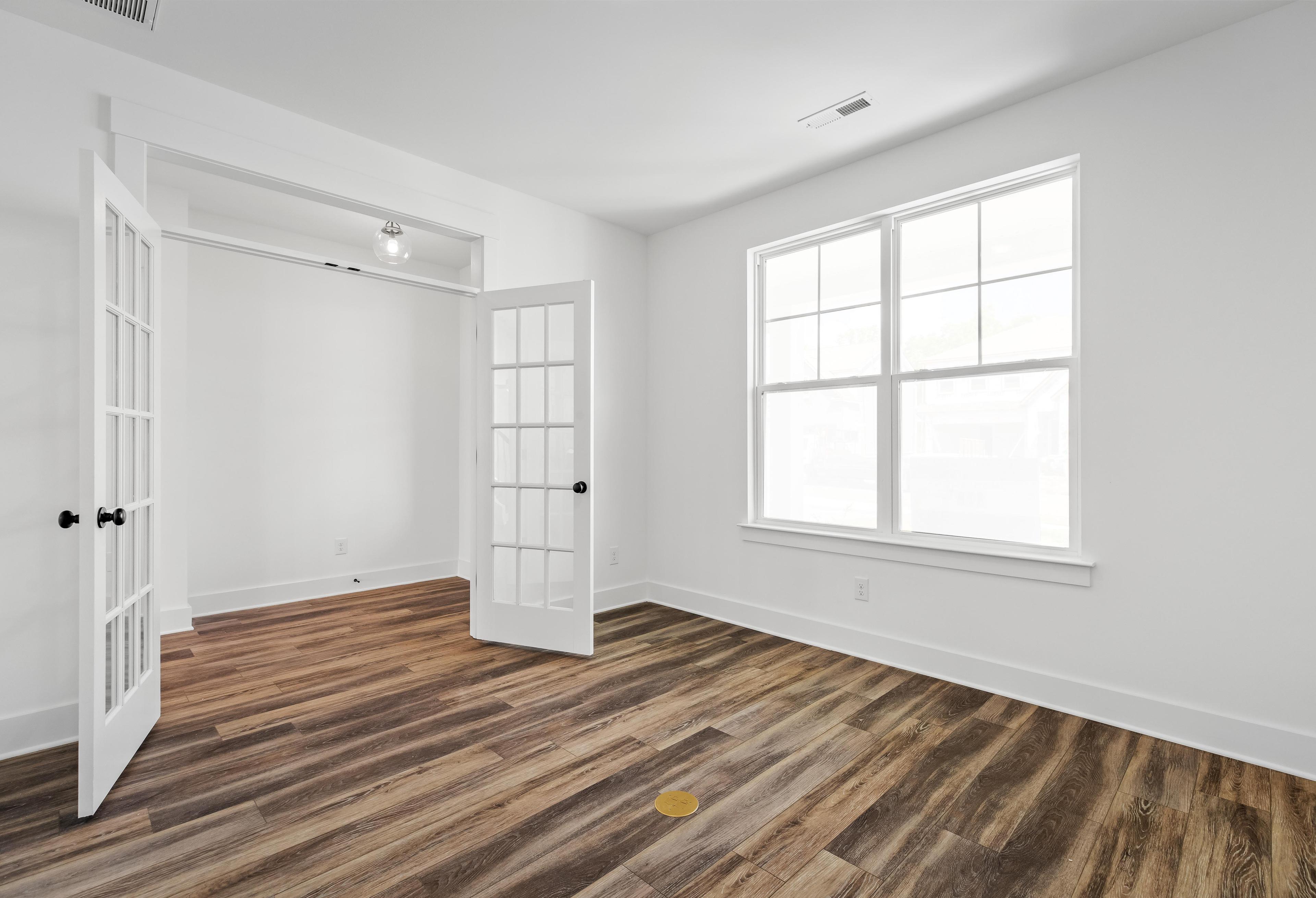 Bright home office or flex room in The Cedar D featuring French doors, wood-look flooring, and natural light.