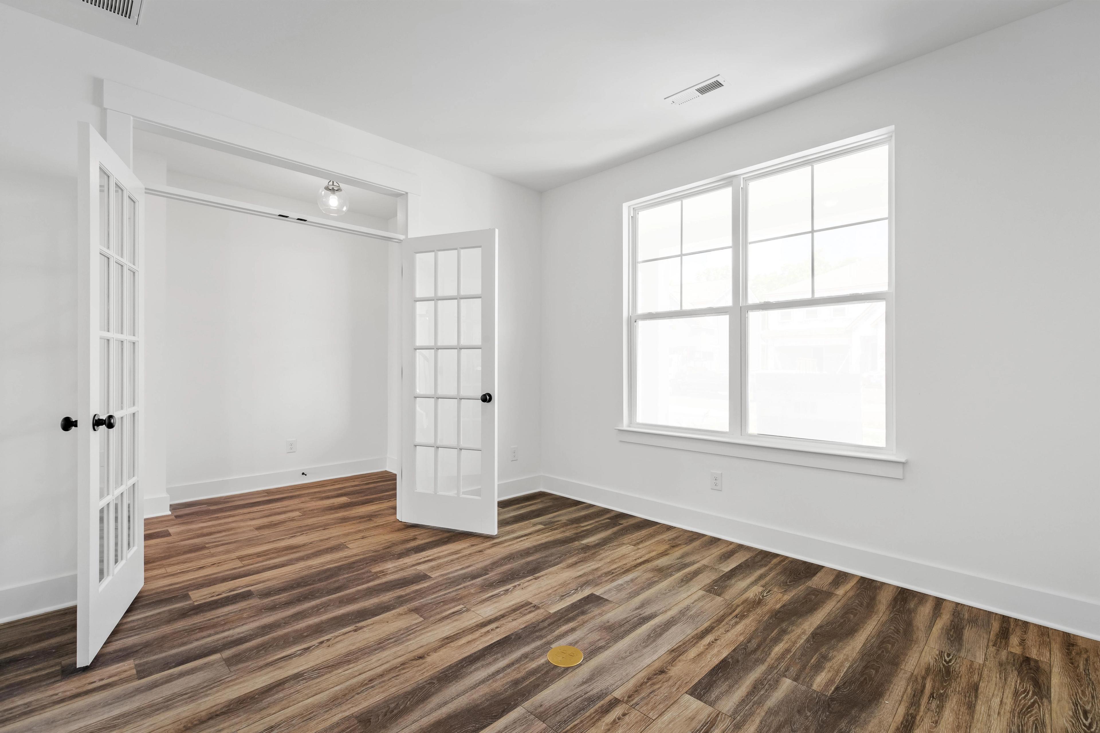 Bright home office or flex room in The Cedar D featuring French doors, wood-look flooring, and natural light.