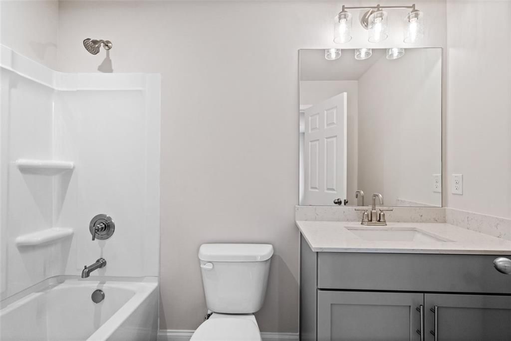 Modern bathroom featuring white bathtub, shower, gray vanity and mirror in Davidson Homes The Hickory B at Wehunt Meadows, Hoschton, GA