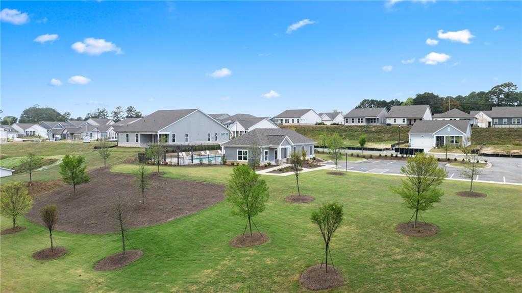 Aerial view of modern single-story homes, green lawns, young trees, and fenced community pool in Kelly Preserve, Loganville, Georgia