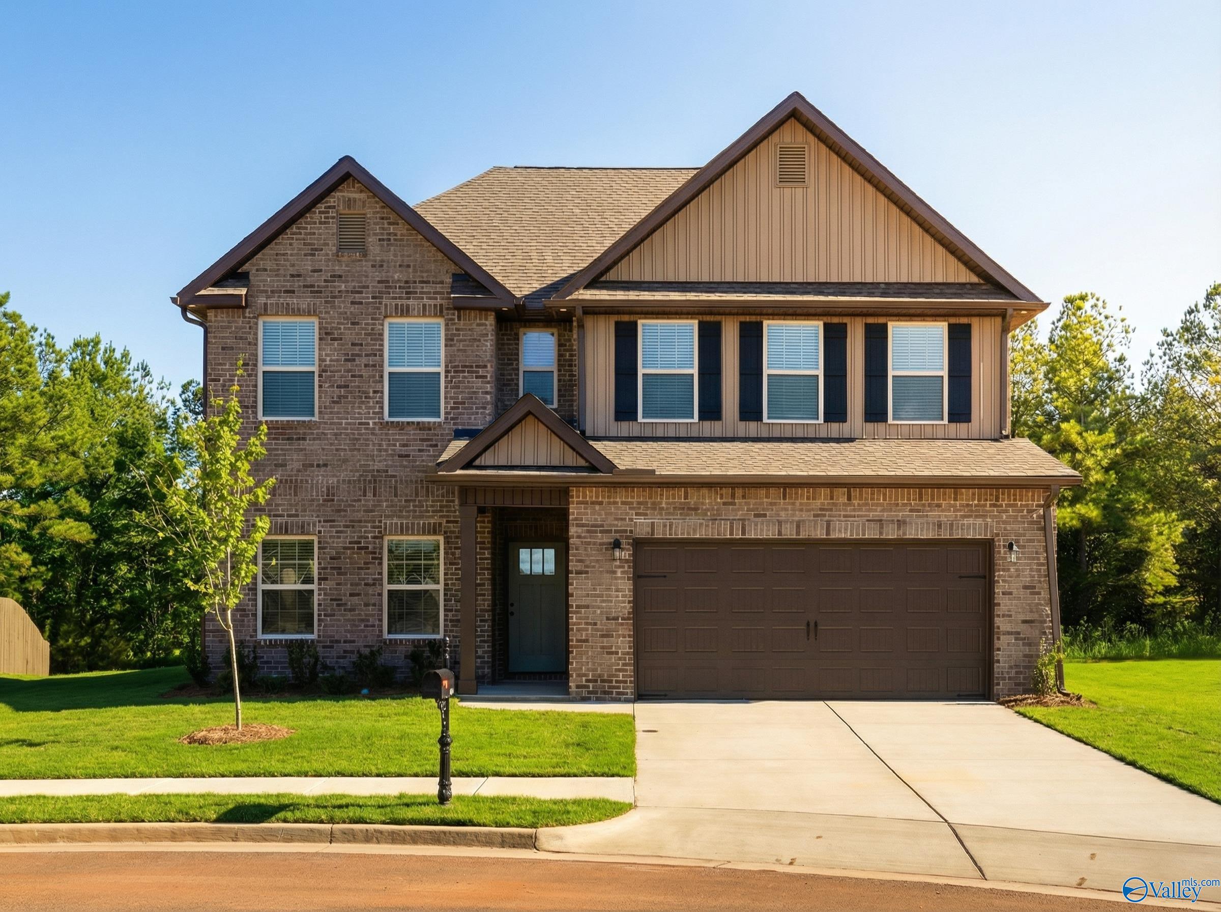 Two-story brick home with 2-car garage, manicured lawn, and mature trees in Ricketts Farm, Athens, Alabama - Davidson Homes Shelby A