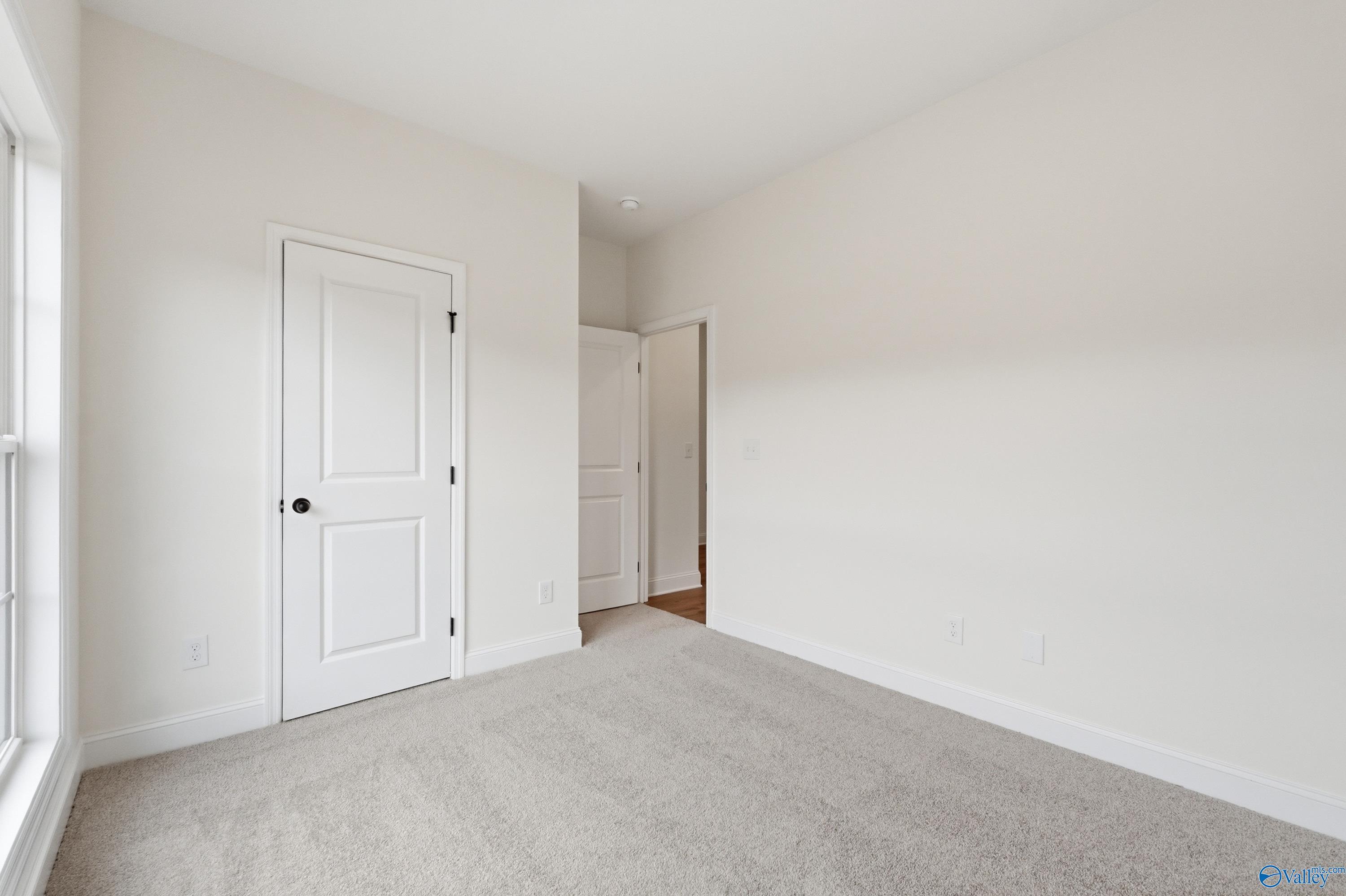 Bright, neutral bedroom with plush carpet in The Asheville C floor plan at The Highlands in Arab, Alabama.