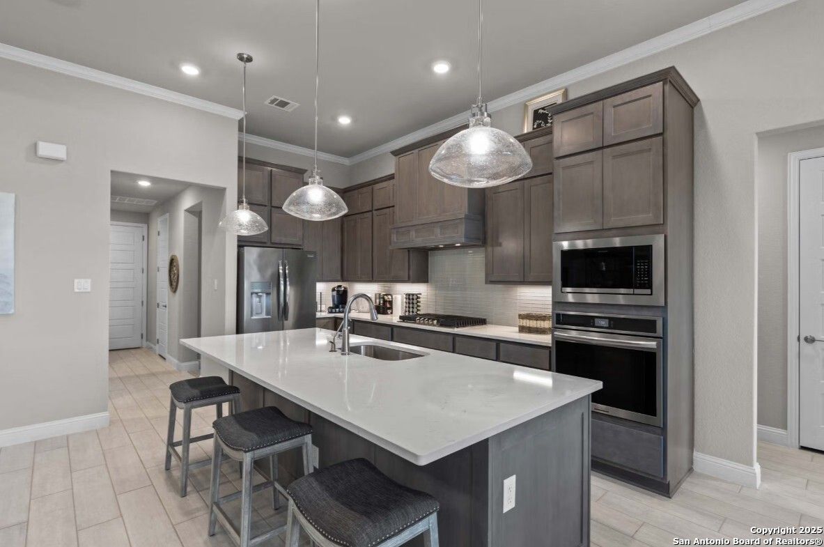 Modern kitchen with quartz island, stainless appliances, and shaker cabinets in The Garner B by Davidson Homes, Ladera, San Antonio