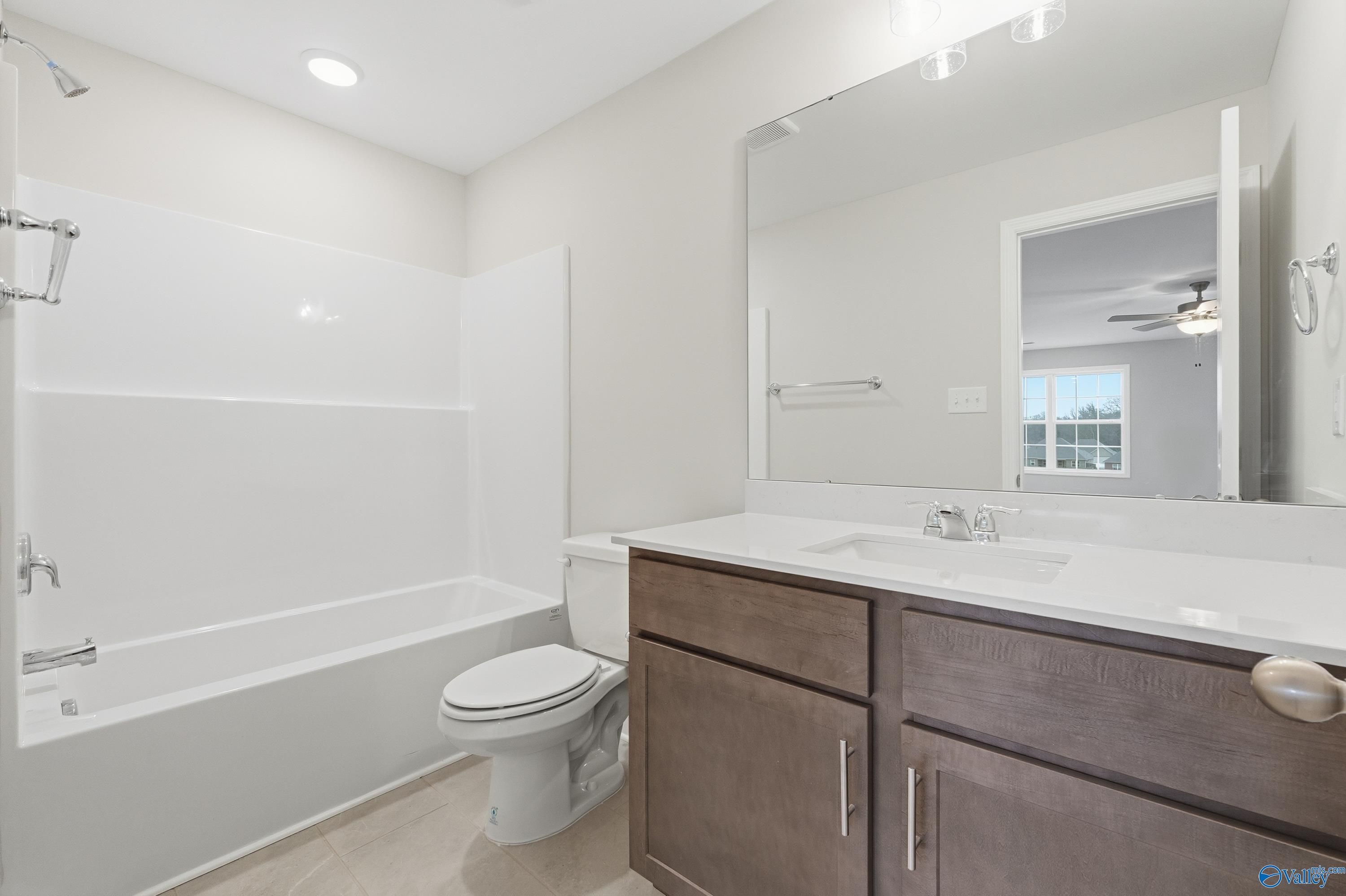 Modern bathroom with white subway tile shower-tub combo, double vanity, and large mirror in Davidson Homes The Kirkland, Decatur, Alabama