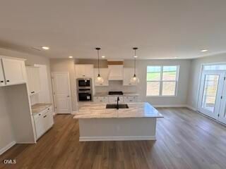 Modern kitchen with white cabinets, island, and stainless appliances in The Ash C plan at Woodland Crossing, Zebulon, NC.
