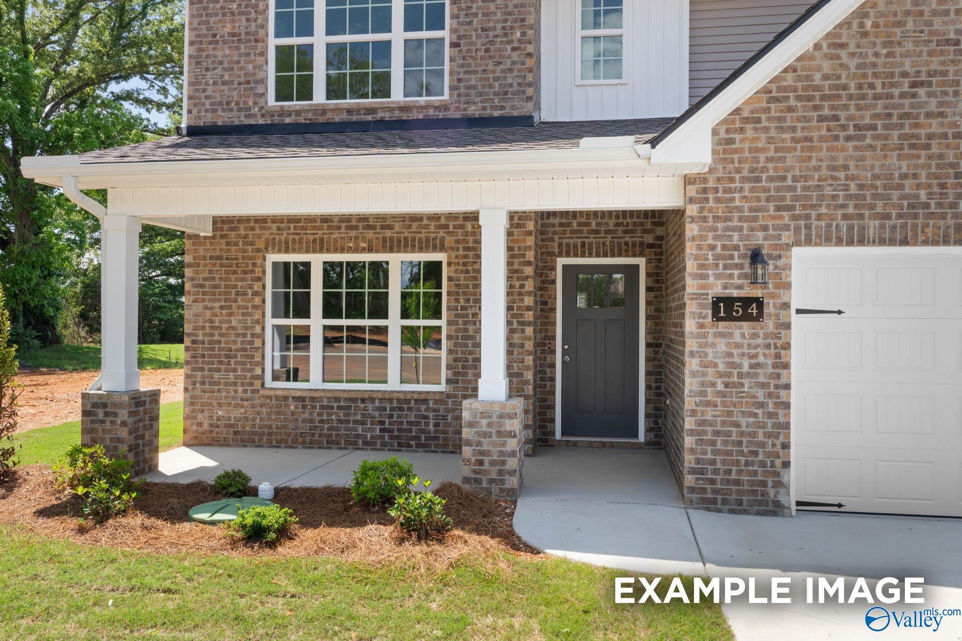 Two-story brick home with covered porch, columns, gray front door, and two-car garage in Walker's Hill, Meridianville, Alabama