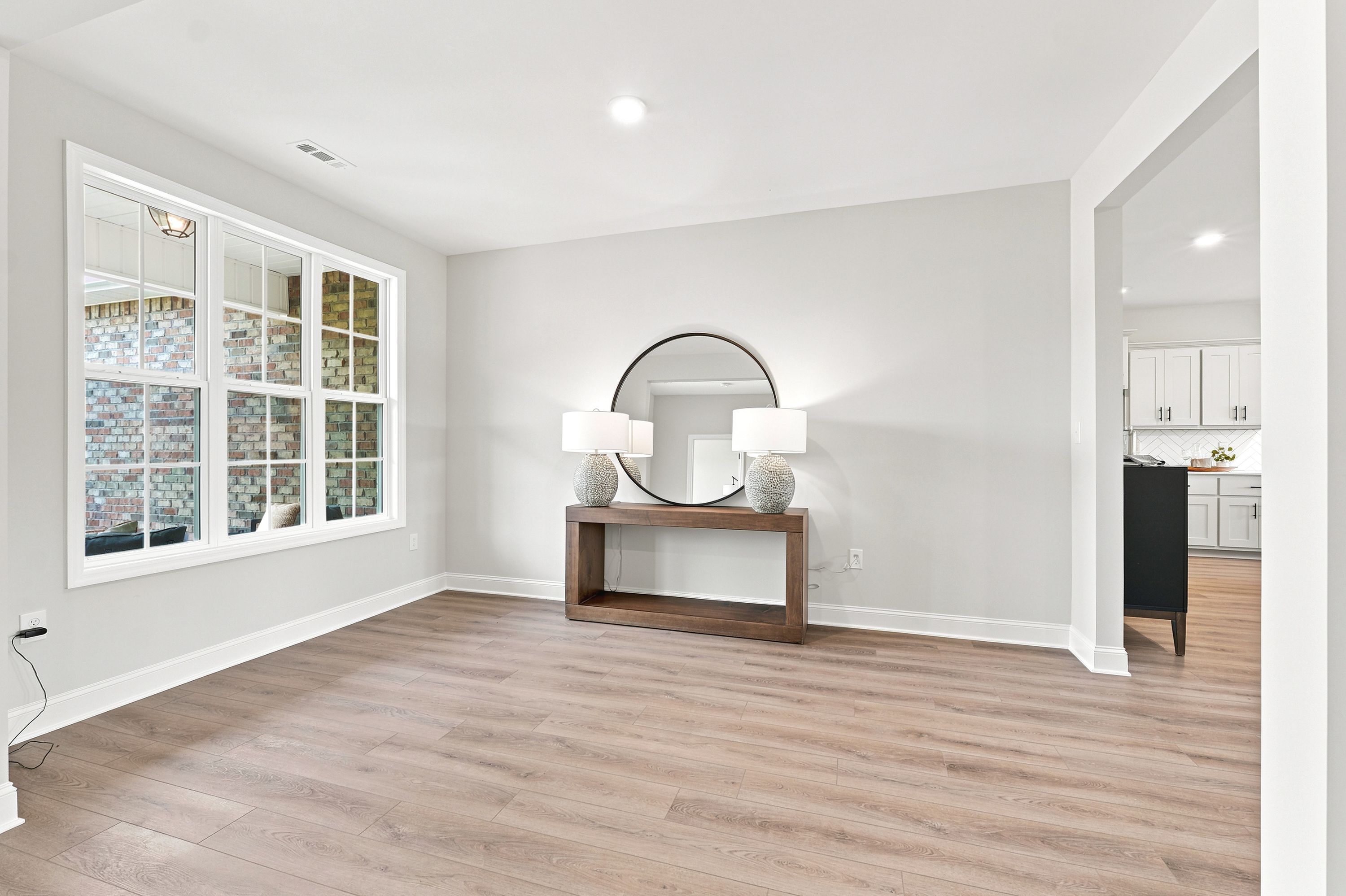 Bright dining area at Riverton Preserve in Huntsville, AL featuring wood-look flooring, console table, and round mirror.