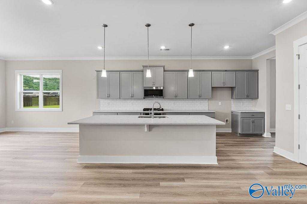 Modern open-concept kitchen with gray cabinets, white quartz island, stainless appliances in The Oxford 5-bedroom home, Owens Cross Roads