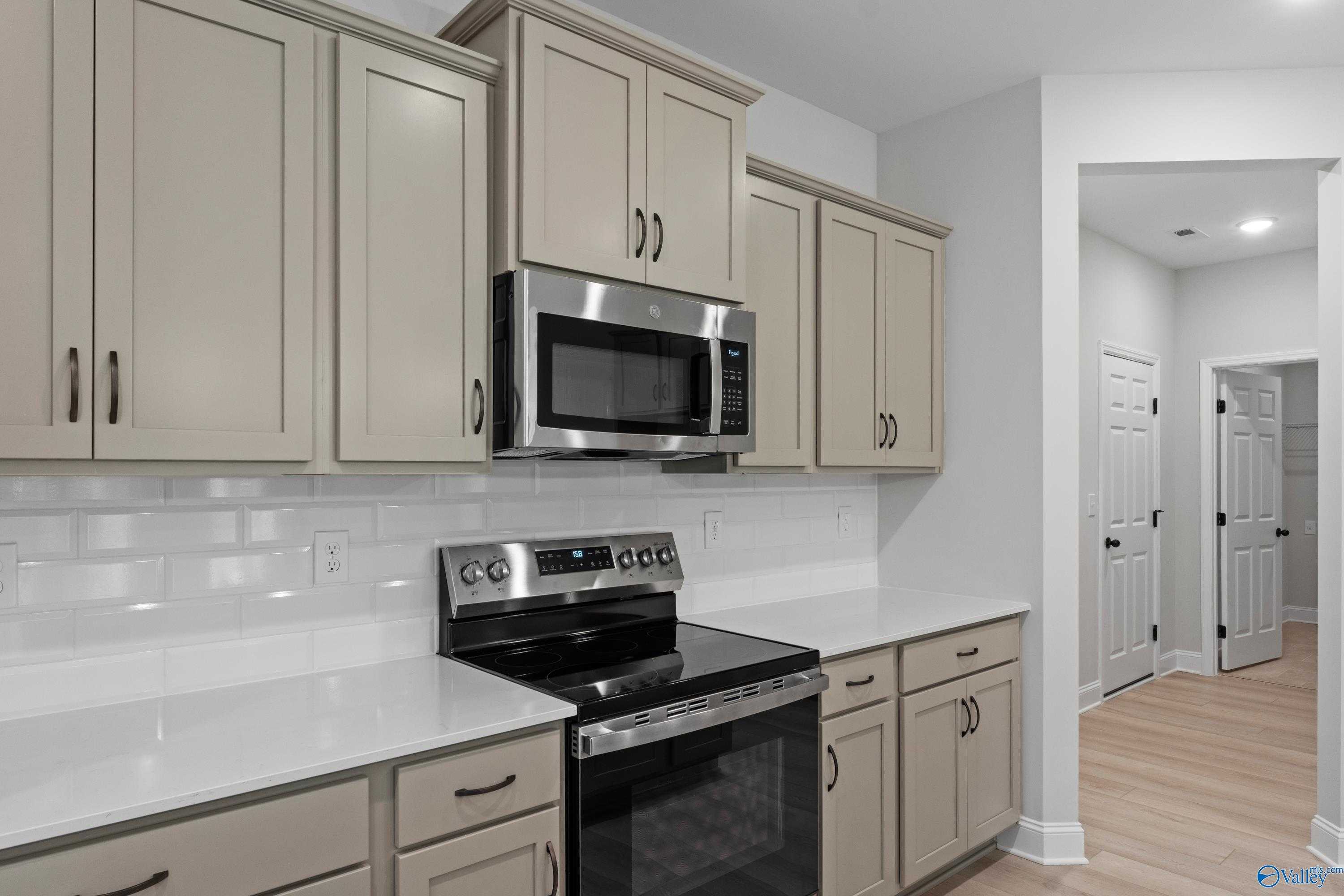Modern kitchen featuring beige shaker cabinets, stainless steel range and microwave, white quartz counters in The Kirkland with Bonus, Harvest AL