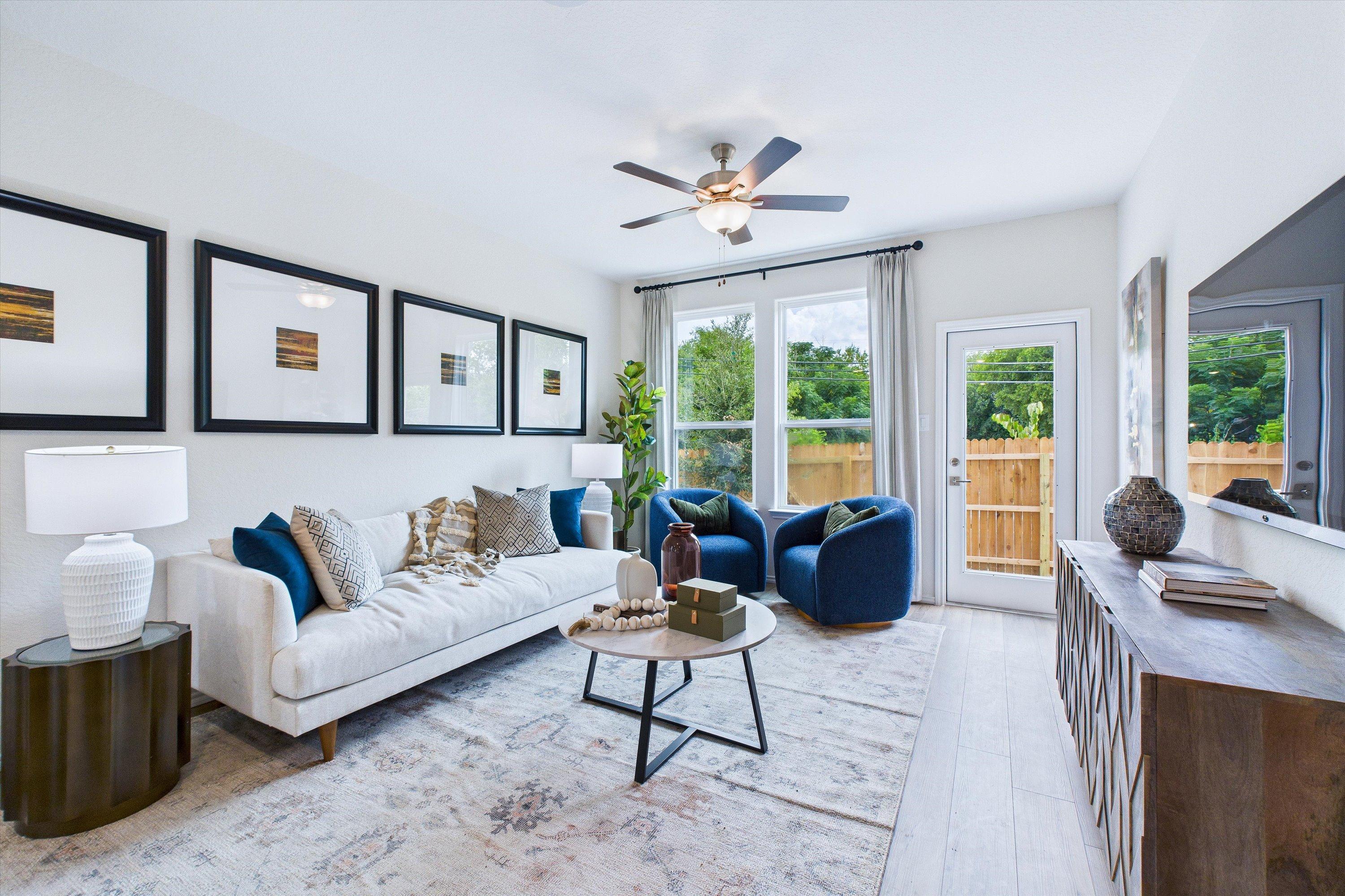 Spacious living room in Cedar Heights San Antonio TX home by Davidson Homes featuring white sofa, blue velvet chairs, ceiling fan, large windows and French doors to patio