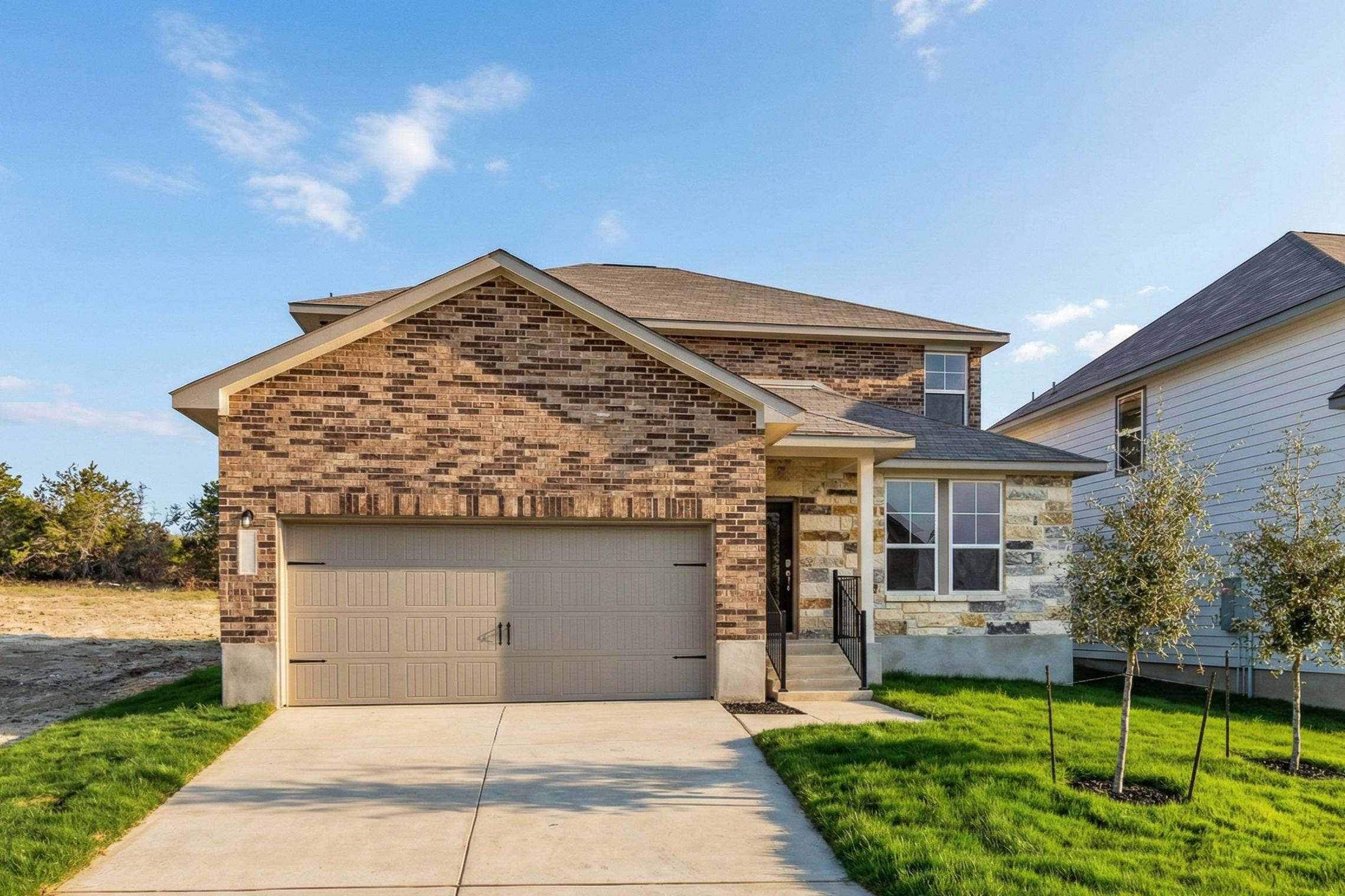 Modern brick home exterior at Royal Crest in San Antonio TX with two-car garage, covered porch, and green lawn by Davidson Homes