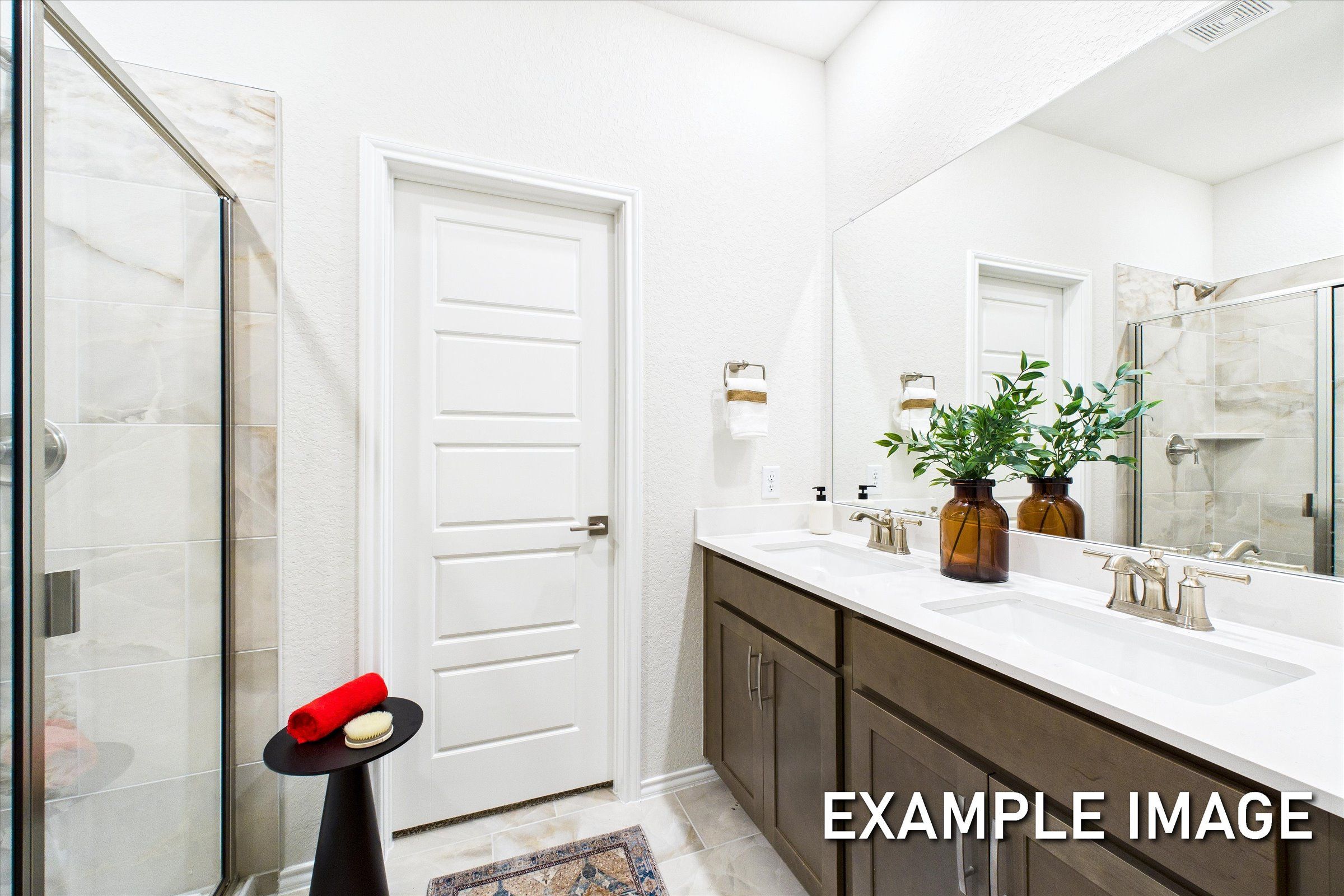 Spacious master bathroom in The Brazos A with double vanity, glass shower, large mirror, and potted plants