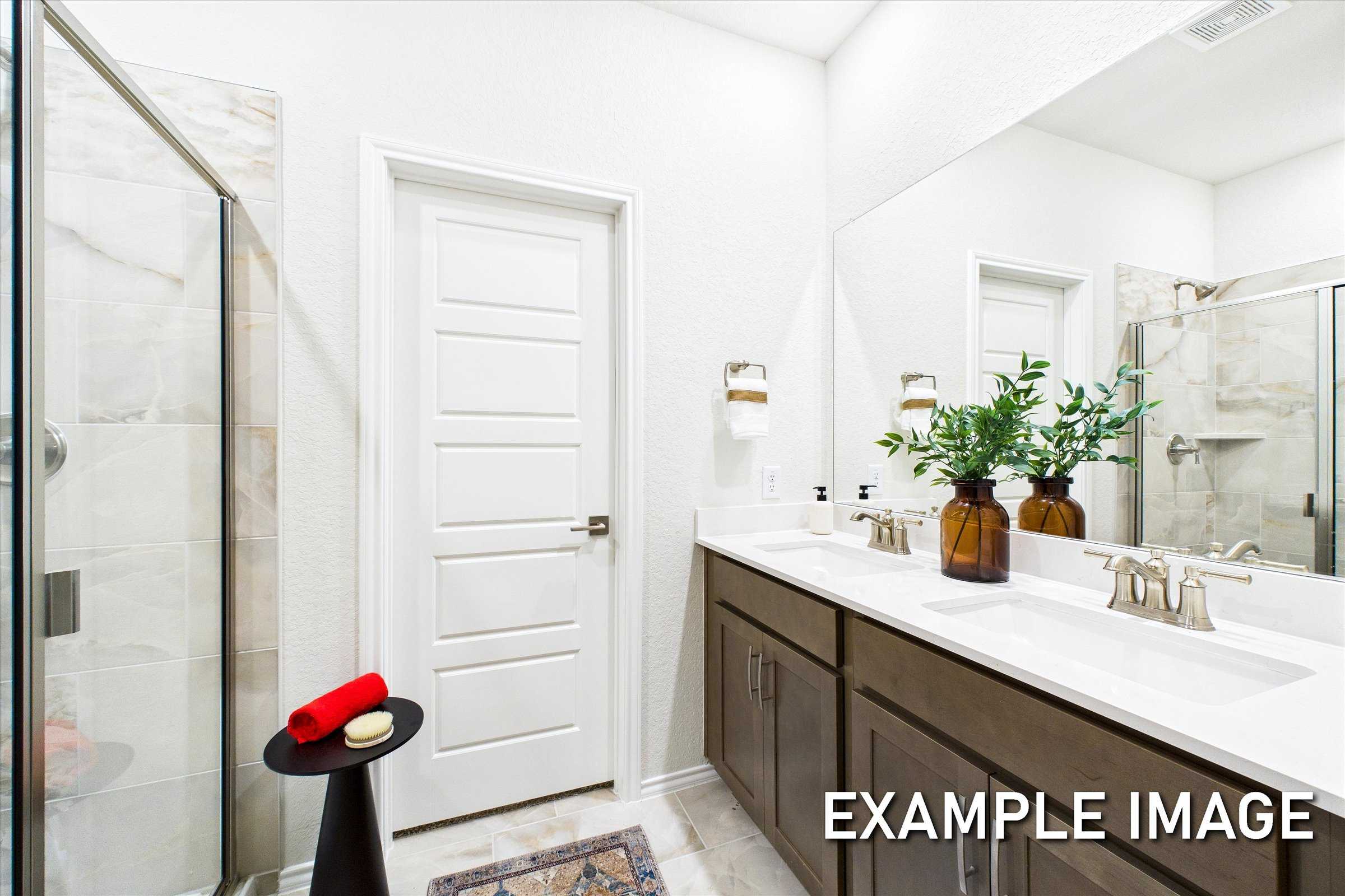 Spacious master bathroom in The Brazos A with double vanity, glass shower, large mirror, and potted plants
