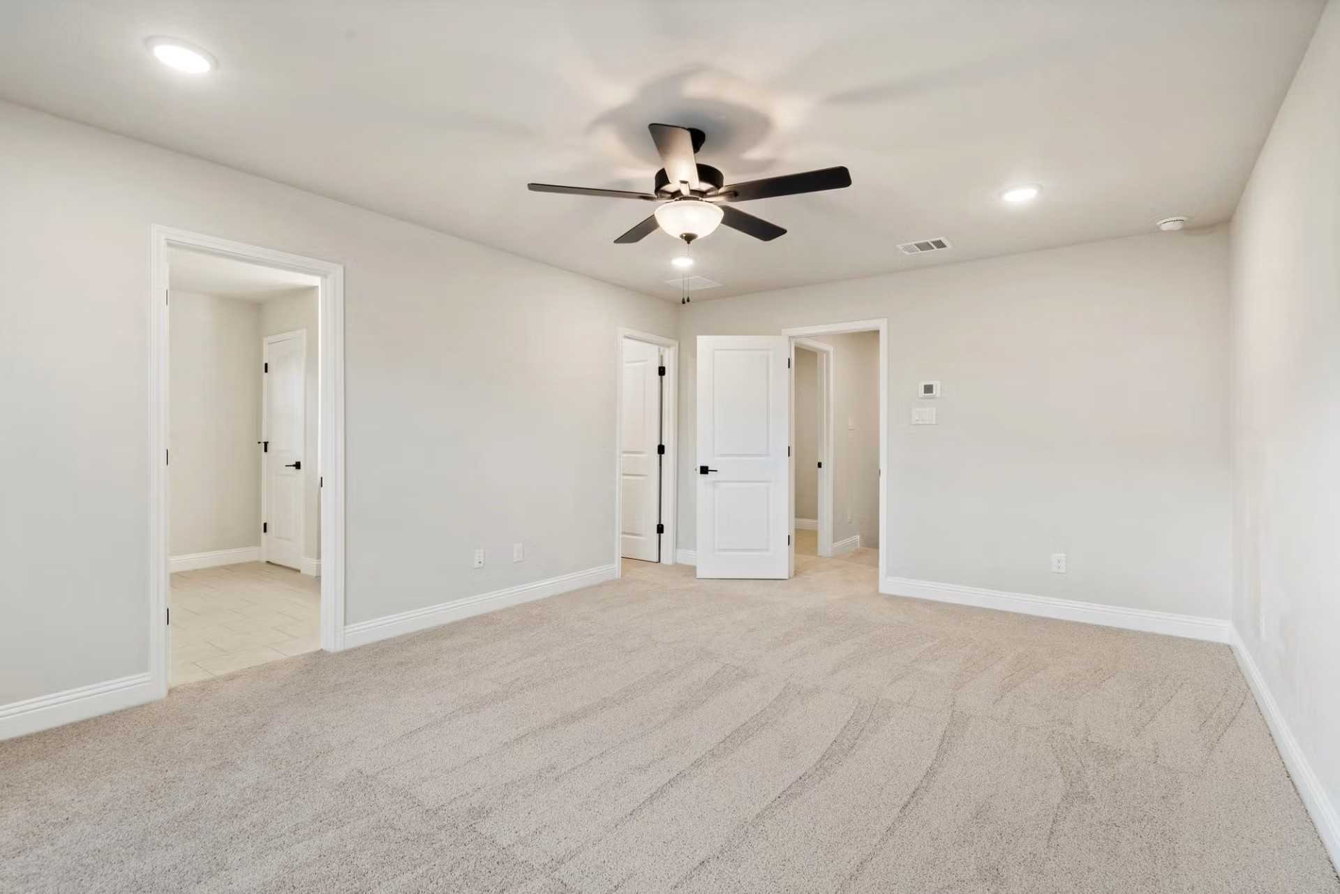 Spacious secondary bedroom with ceiling fan, beige walls, carpet floor, and adjacent doors in Davidson Homes The Wake D, Wylie, Texas