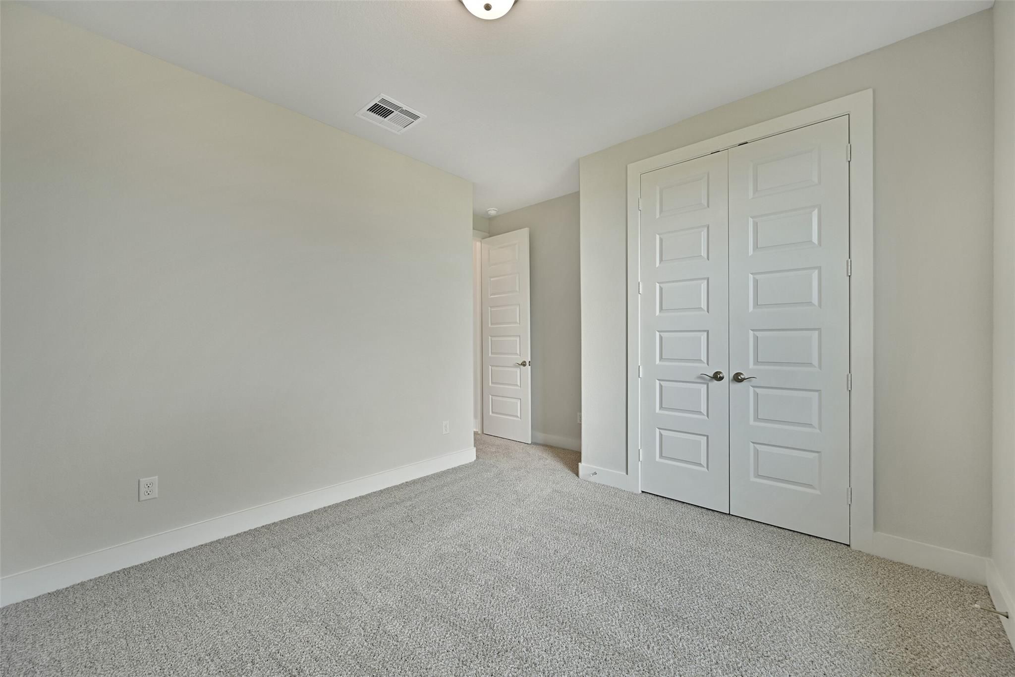 Spacious secondary bedroom with double closet doors, beige walls, and carpet in Davidson Homes The Edward A, Lago Mar, Texas City