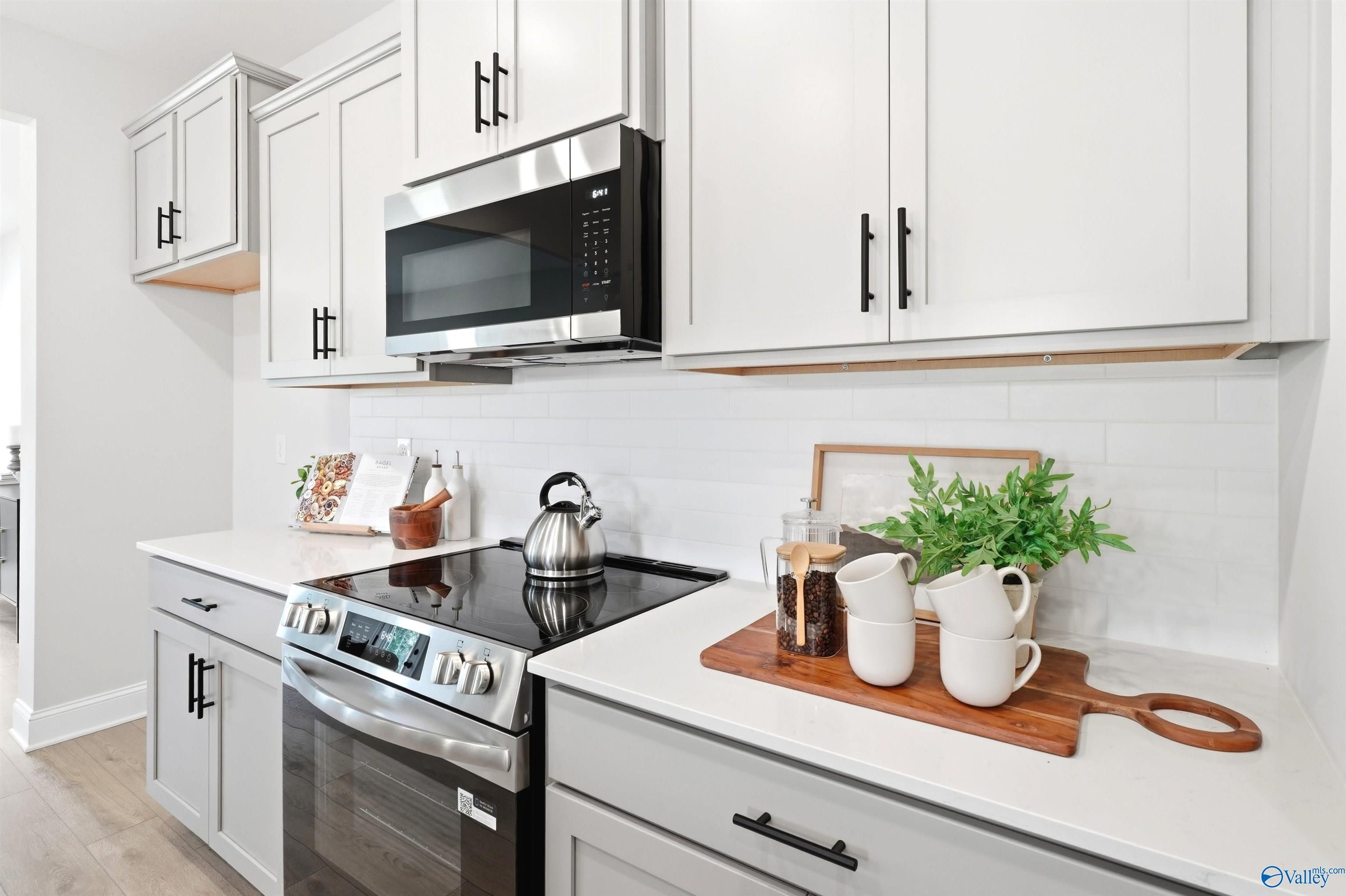 Modern white kitchen with stainless steel appliances, subway tile backsplash, and quartz countertops in Davidson Homes The Russell A, Huntsville