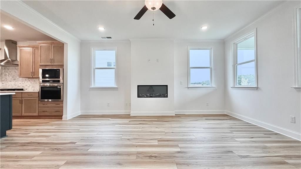Open-concept living room with fireplace and wood-look floors in The Glenwood A floor plan at Wehunt Meadows, Hoschton.