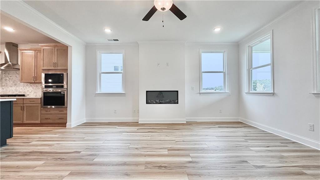 Open-concept living room with fireplace and wood-look floors in The Glenwood A floor plan at Wehunt Meadows, Hoschton.