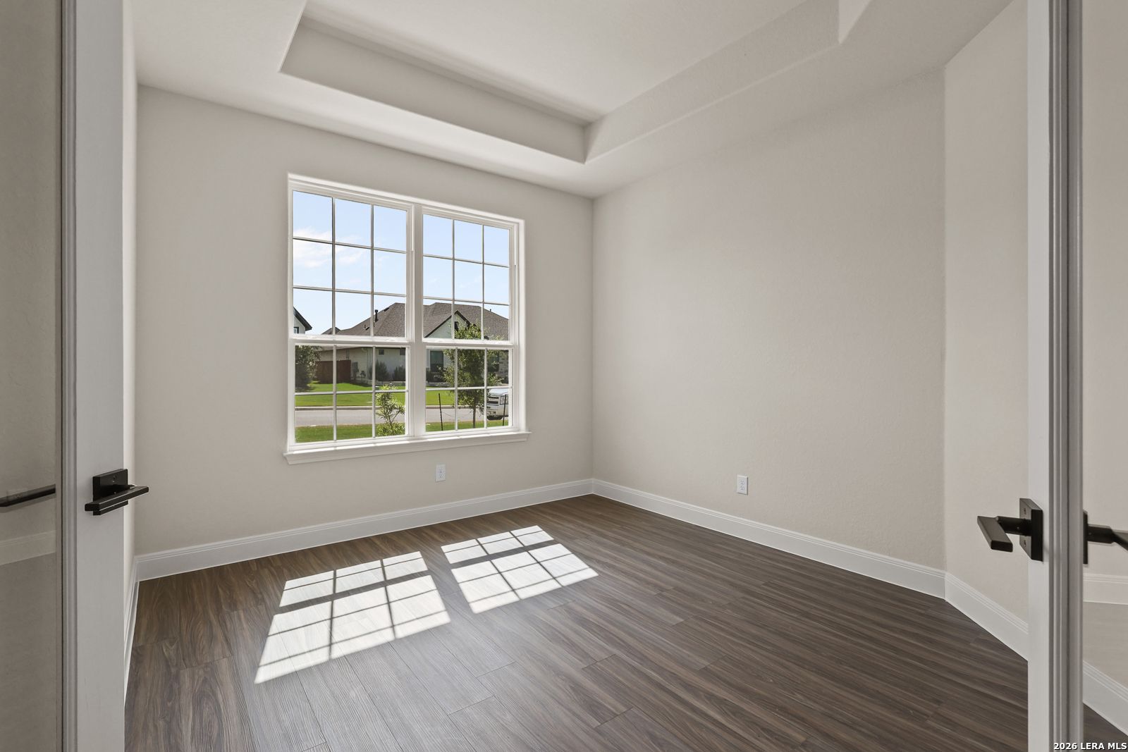 Bright home office or bedroom with tray ceiling and wood-style flooring in Davidson Homes Summerlin B, Potranco Oaks.