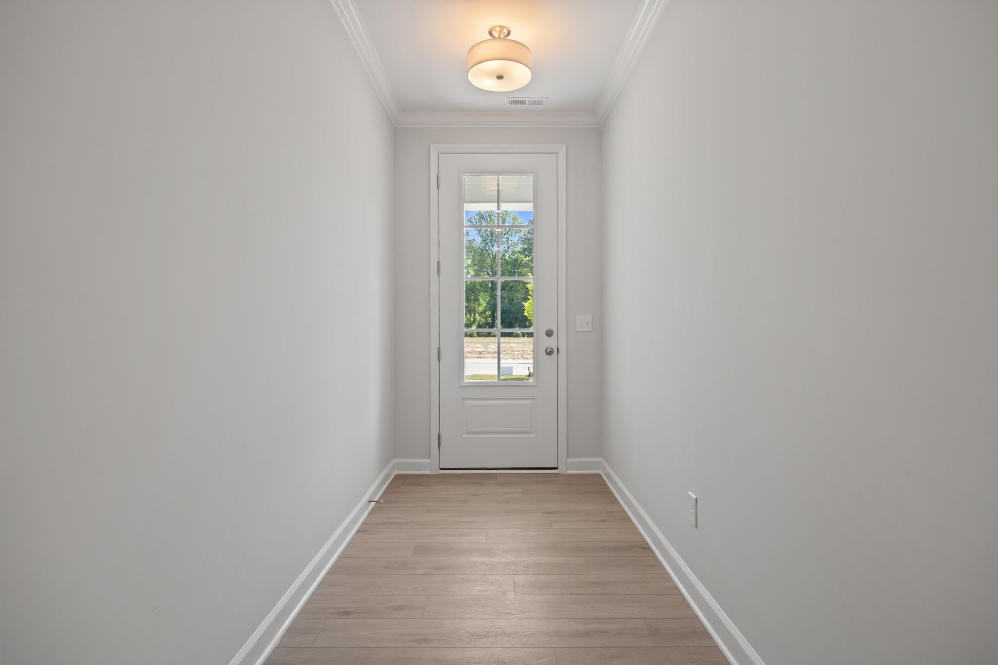 Bright entryway hallway in The Ashport C floor plan featuring light wood flooring and a glass-paneled door.
