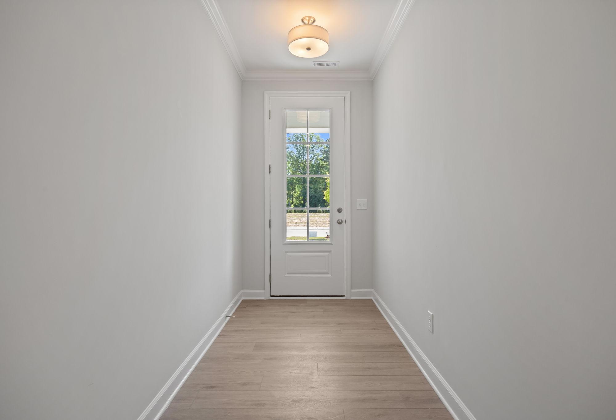 Bright entryway hallway in The Ashport C floor plan featuring light wood flooring and a glass-paneled door.