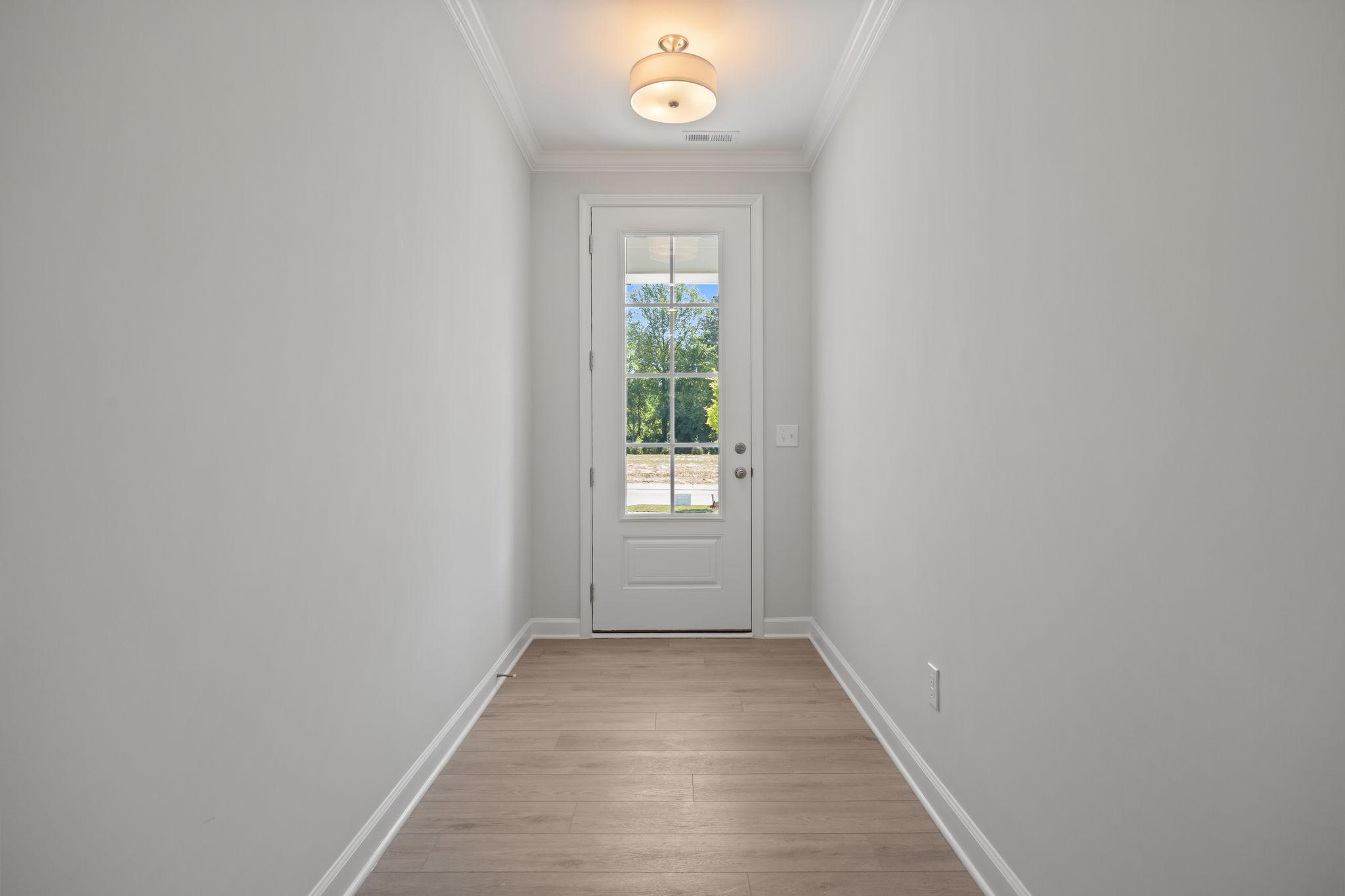 Bright entryway with light hardwood floors and glass-paneled door in The Ashport B home design by Davidson Homes.