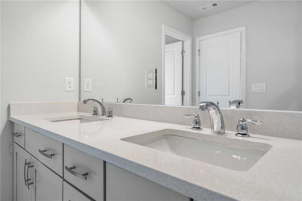 Modern double vanity with quartz countertops, chrome faucets, and mirrors in master bath of The Cary A by Davidson Homes, Kennesaw, Georgia