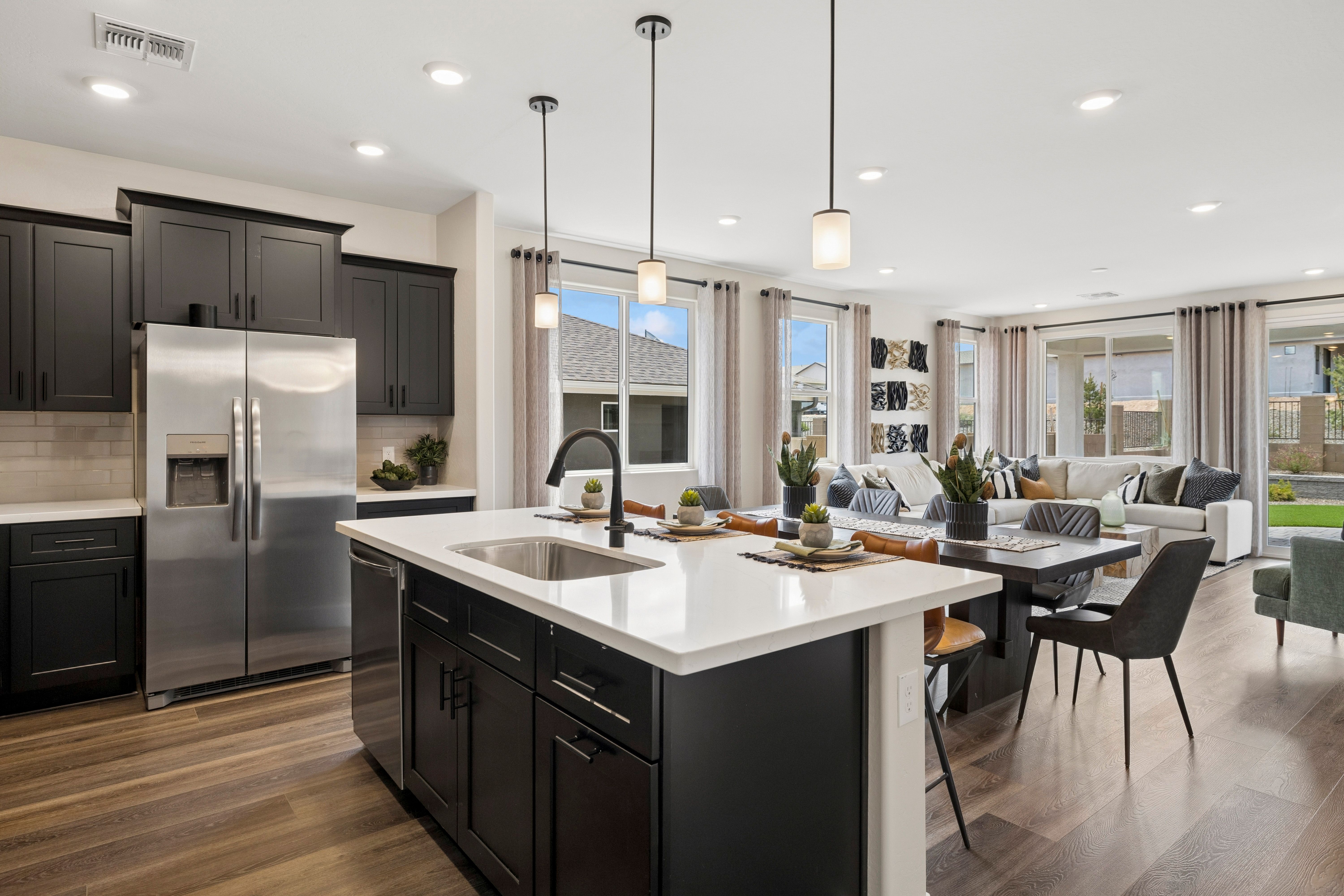 Open-concept kitchen at South Ranch Western Collection in Prescott AZ with black cabinets, white quartz island, stainless appliances, and living area