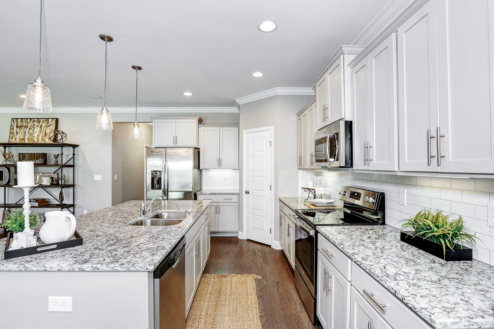 Spacious modern kitchen in Stone Creek Phase II Cullman AL featuring white shaker cabinets, granite island, stainless appliances