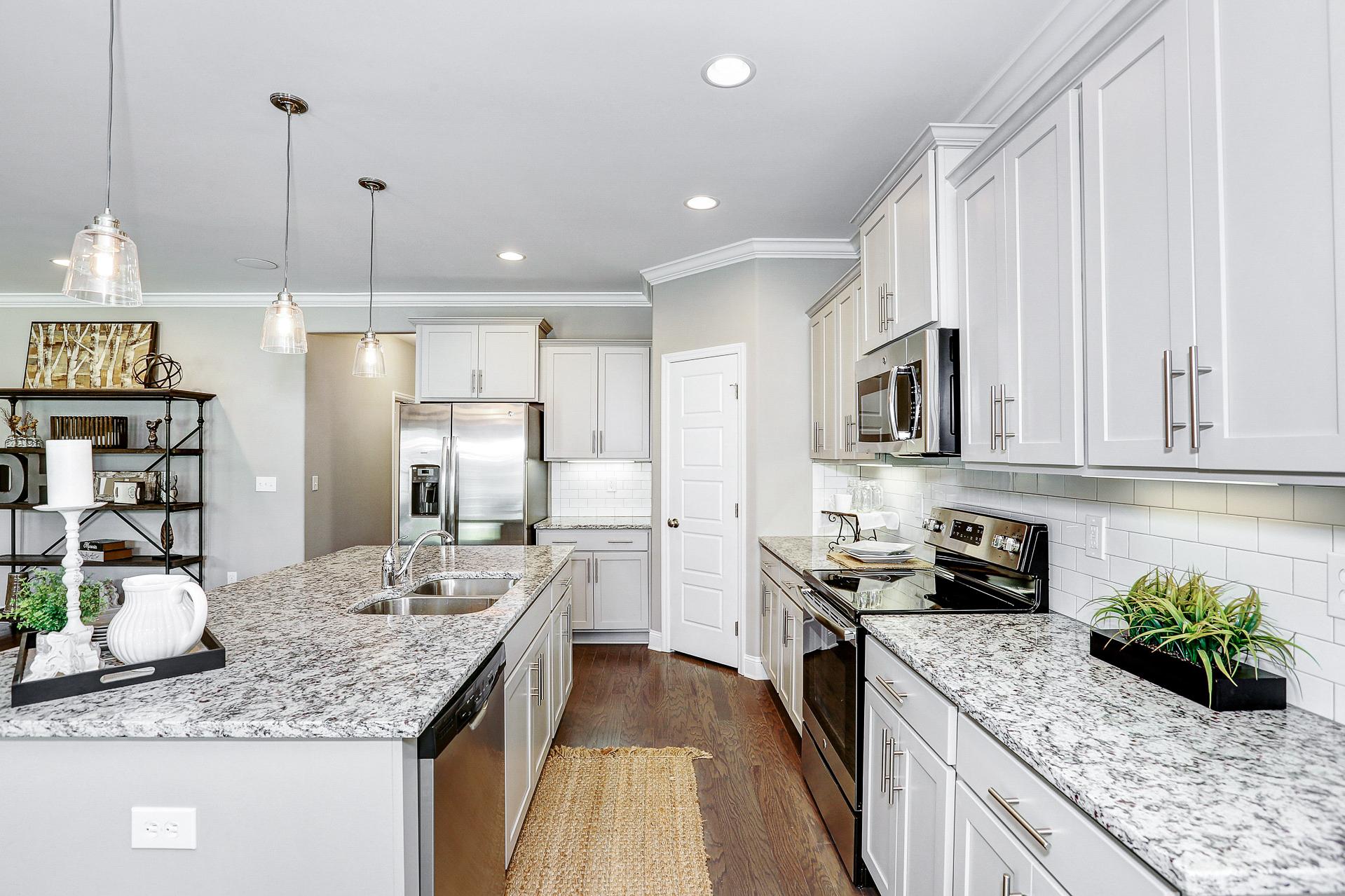 Spacious modern kitchen in Stone Creek Phase II Cullman AL featuring white shaker cabinets, granite island, stainless appliances