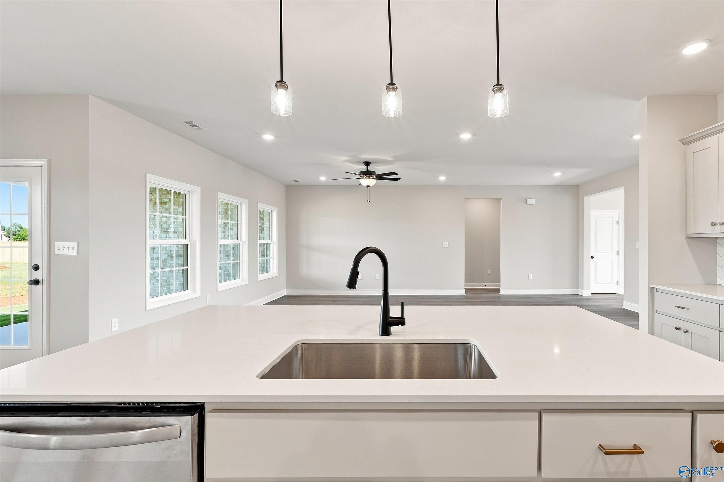 Modern kitchen island with quartz countertops and pendant lighting in The Oxford floor plan, Kendall Farms, Toney, Alabama.
